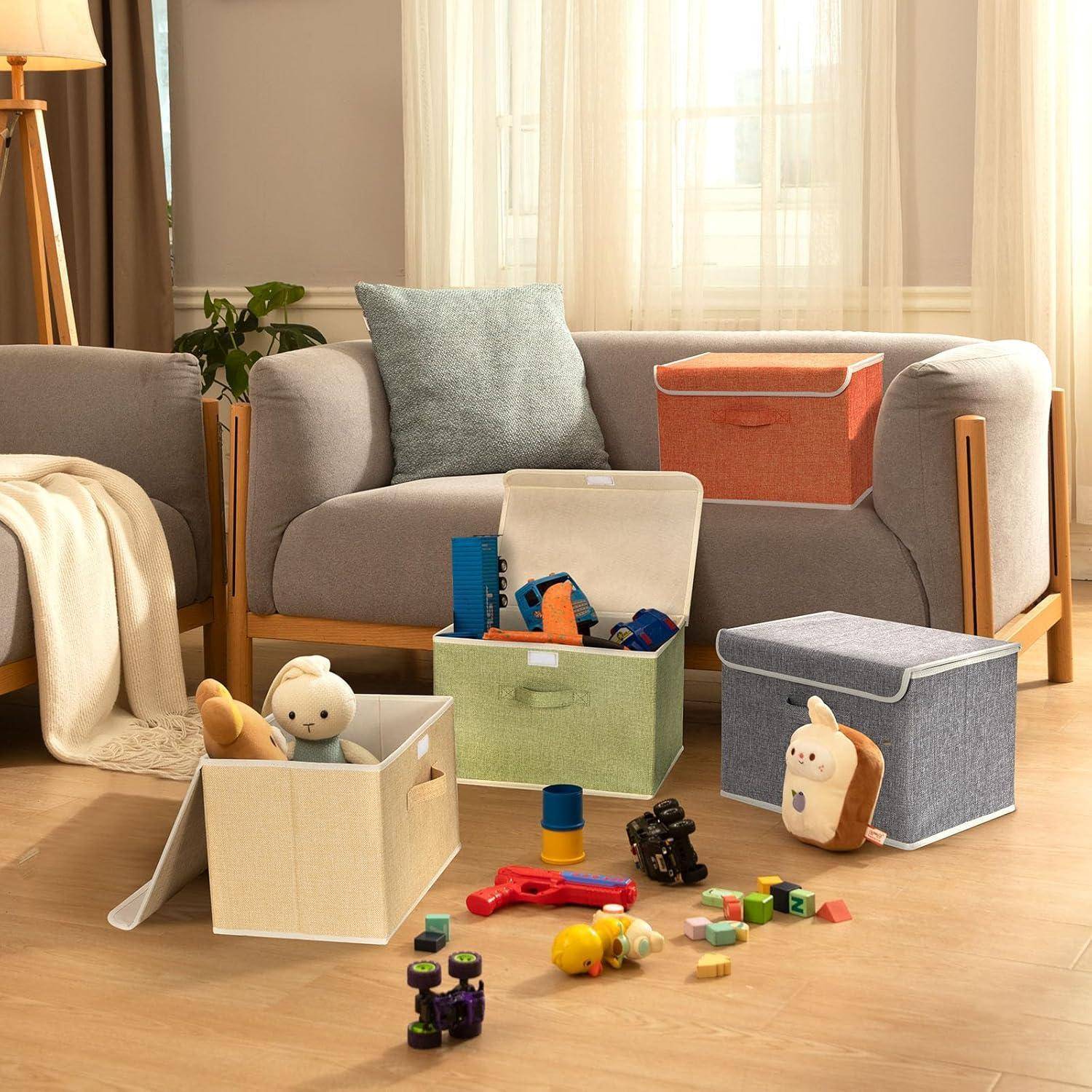 Ein gemütliches Wohnzimmer mit hellgrauen Sofas, auf dem Boden sind Spielzeuge ordentlich in bunten Stoffboxen aufbewahrt, was auf einen gut organisierten Spielbereich hinweist.