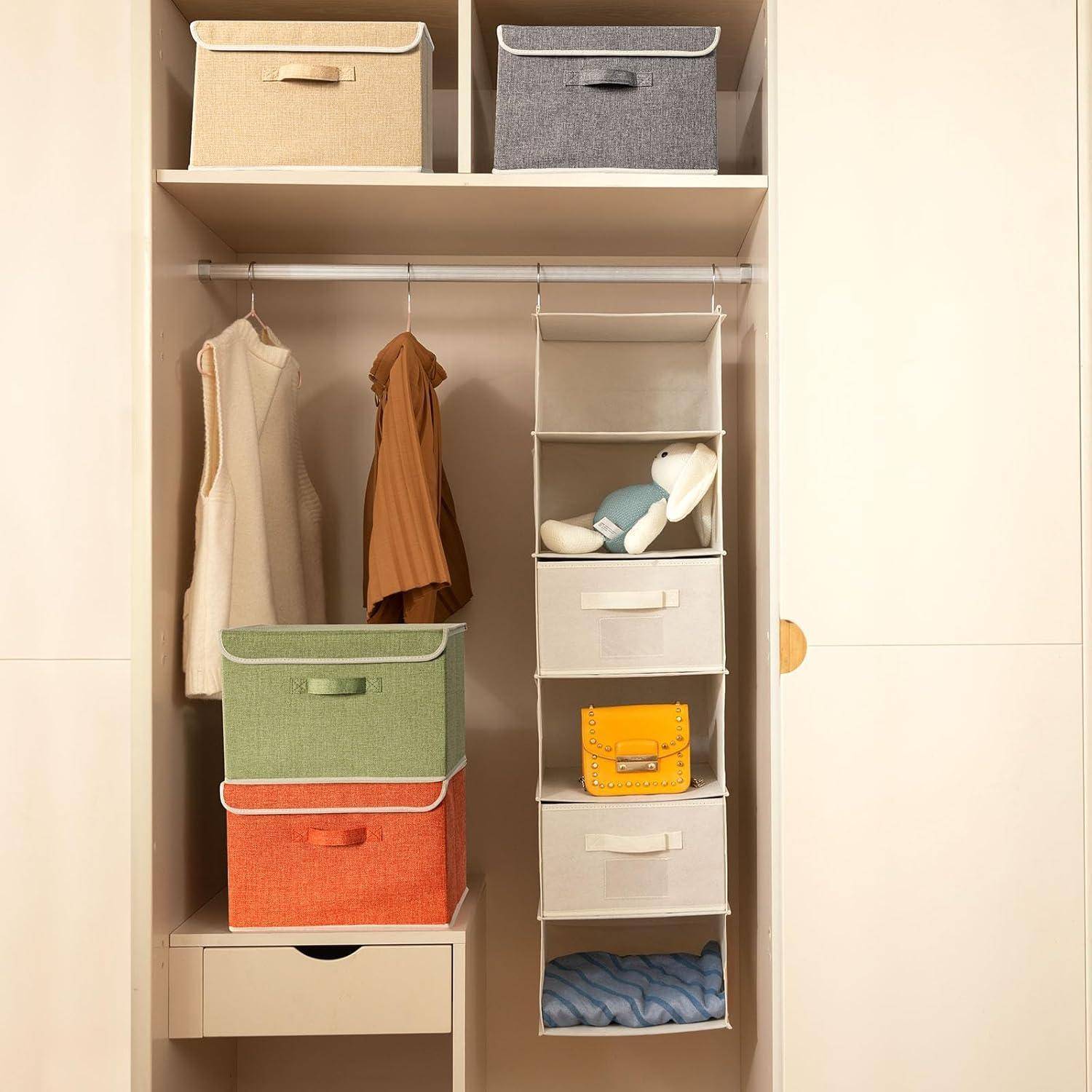 Ein organisierter Kleiderschrank mit Aufbewahrungsboxen in verschiedenen Farben, hängenden Kleidungsstücken und einem Plüschtier.