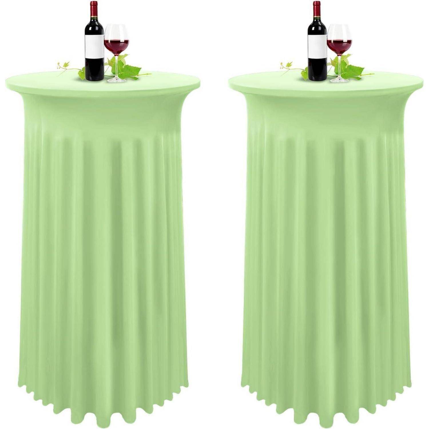 Zwei hohe, runde Tische, die mit hellgrünen Tischdecken bedeckt sind, wobei jeder Tisch eine Flasche Rotwein, ein gefülltes Weinglas und eine grüne Serviette trägt.