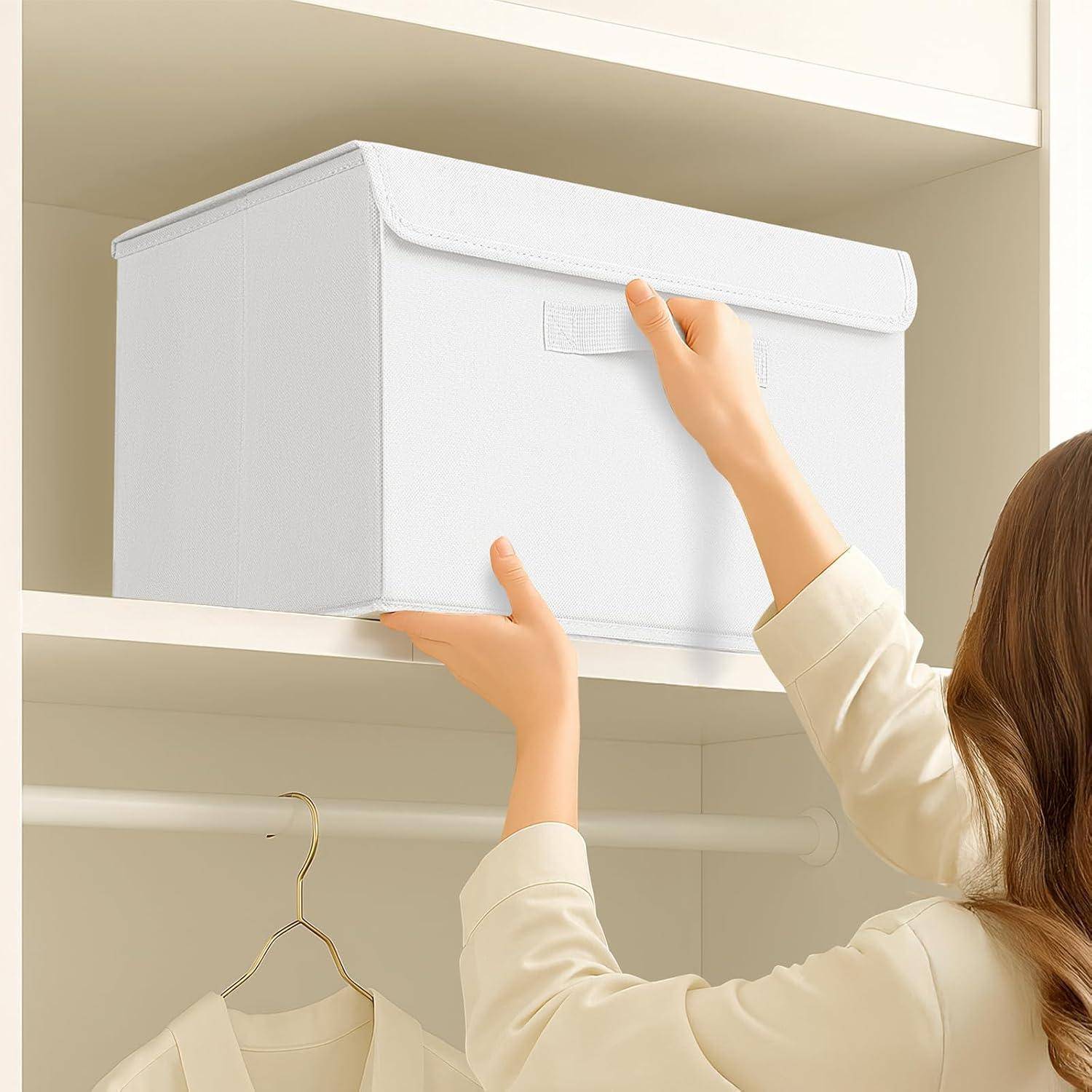 Eine Person streckt sich nach oben, um eine Aufbewahrungsbox auf ein Regalfach im Kleiderschrank zu stellen, wobei ein hängendes Hemd darunter sichtbar ist, was auf eine Organisationsaufgabe hindeutet.