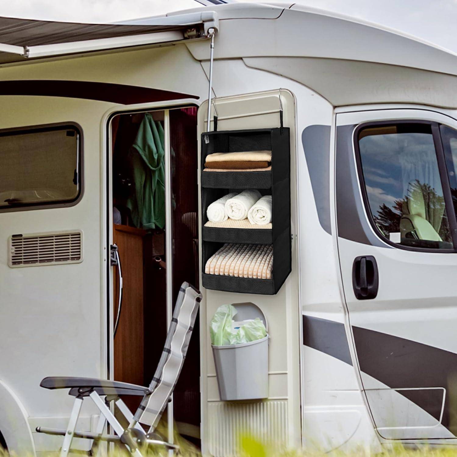 Ein Wohnmobil mit geöffneter Tür, das ein gemütliches Inneres offenbart. Ein hängender Organizer mit Handtüchern ist an der Seite angebracht. Ein Klappstuhl ist draußen aufgestellt.