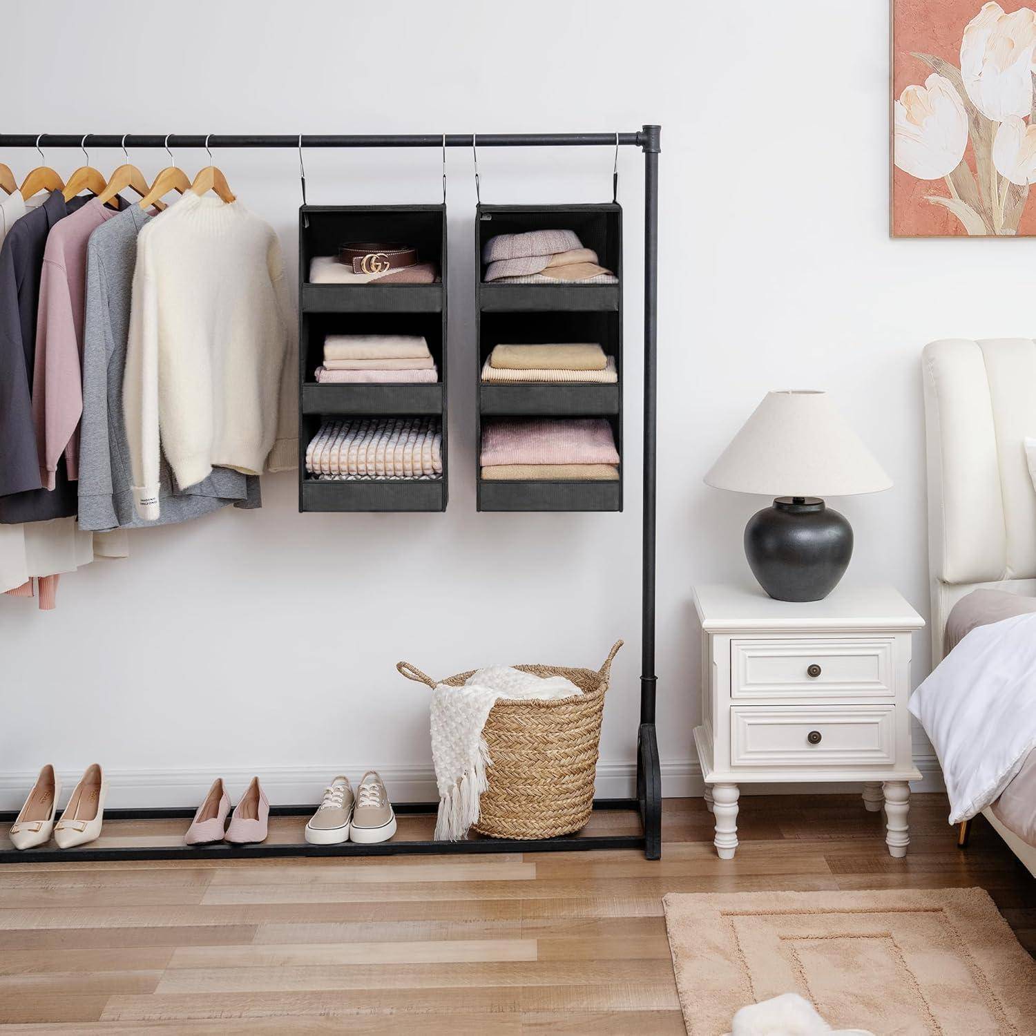 Kleiderstange mit ordentlich arrangierten Kleidungsstücken in einem Schlafzimmer; enthält Jacken, Hemden und Pullover. In der Nähe steht eine Lampe auf einem Nachttisch.