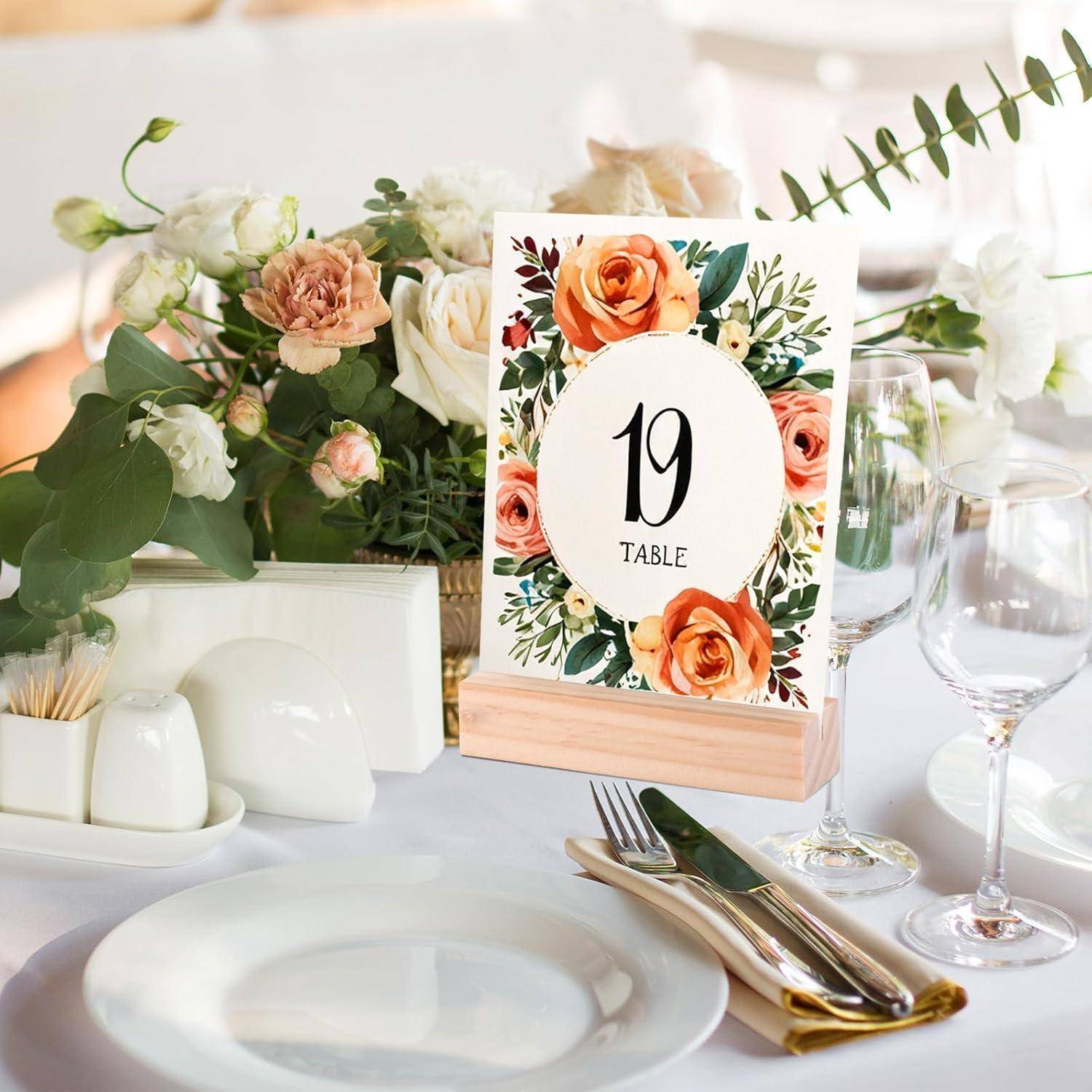 Gedeckter Tisch mit Blumenmittelstück, weißen Tellern, Besteck, Serviette und Tischnummer '19' in einem dekorativen Rahmen.