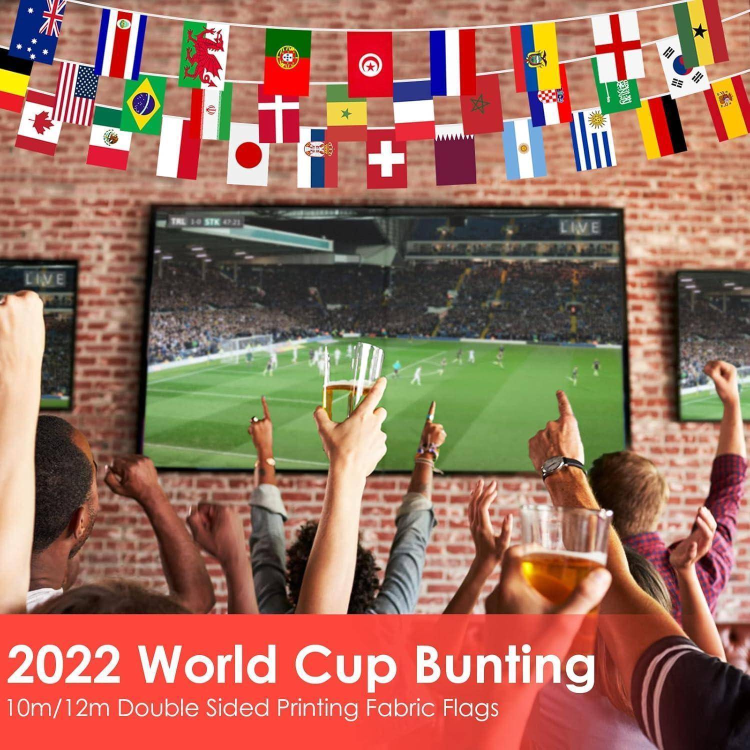 Menschen, die auf eine große Leinwand schauen und bei einem Fußballspiel jubeln. Internationale Flaggen hängen darüber, und ein Banner liest '2022 Weltmeisterschaft Wimpelkette'.