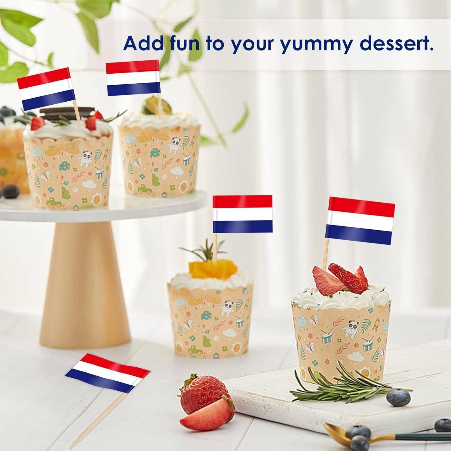 Cupcakes auf einem Ständer, jeder mit einer kleinen Flaggendekoration und bunter Zuckerguss, daneben Erdbeeren und der Text ‚Füge deinem leckeren Dessert Spaß hinzu.