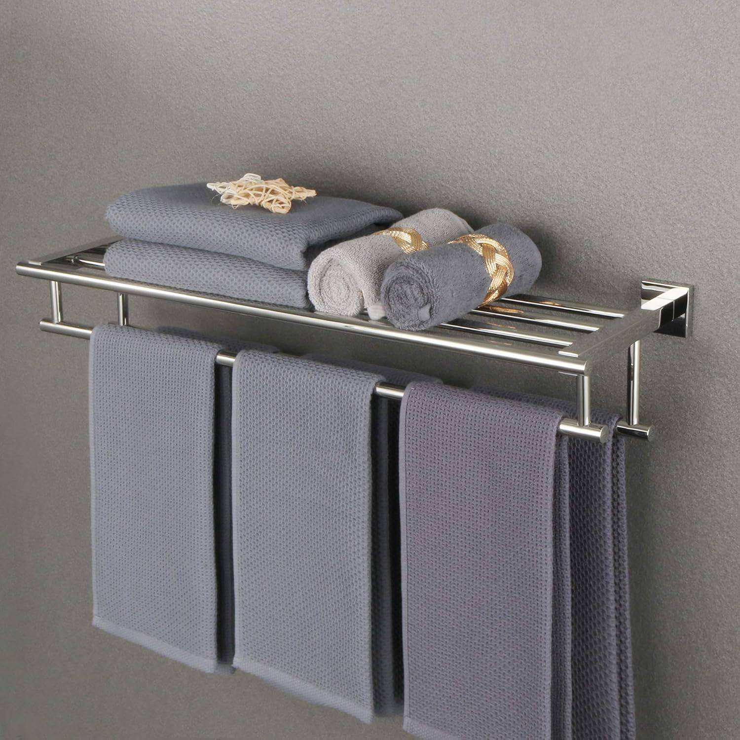 Ein gefalteter Handtuchsatz, bestehend aus großen Handtüchern und kleineren aufgerollten Exemplaren, ordentlich auf einem Metallwandregal in einem modernen, minimalistischen Badezimmer angeordnet.