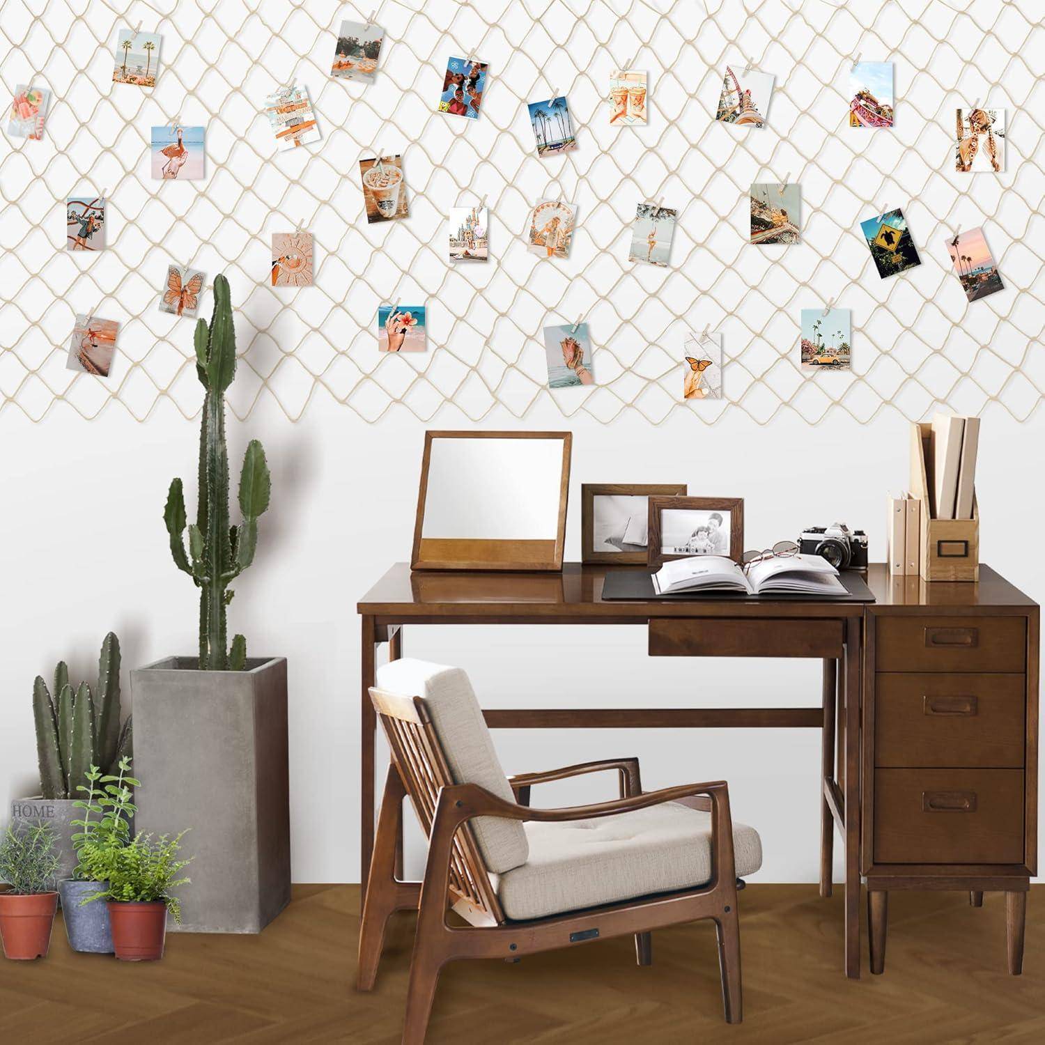 Ein Holzschreibtisch mit einem Spiegel, Büchern und einer Pflanze, neben einem Stuhl. Ein Netz mit hängenden Fotos an der Wand über zwei Topfpflanzen.