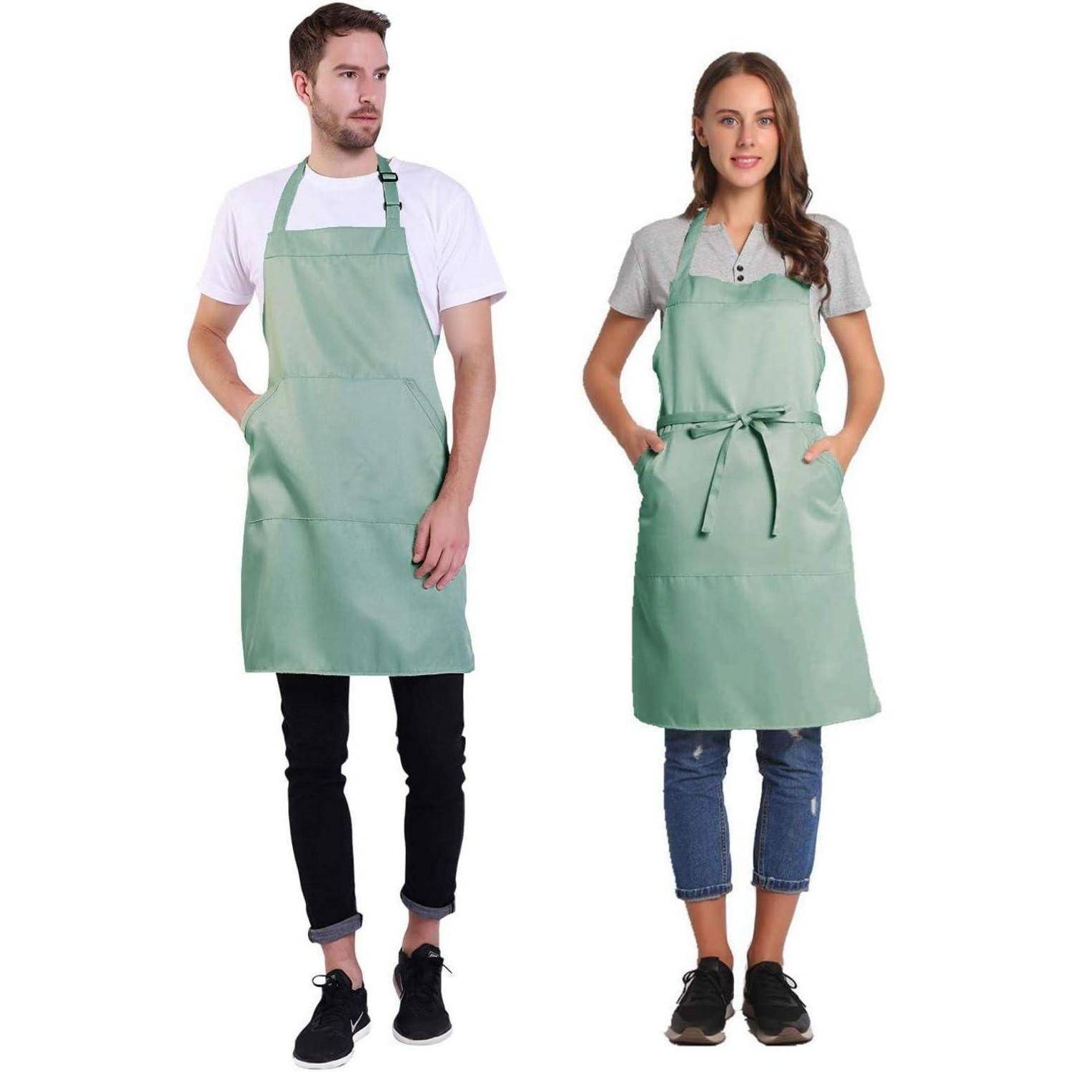 Ein Mann und eine Frau stehen nebeneinander und tragen grüne Schürzen. Der Mann trägt ein weißes Hemd und dunkle Jeans; die Frau trägt ein graues Shirt und hochgerollte Jeans.