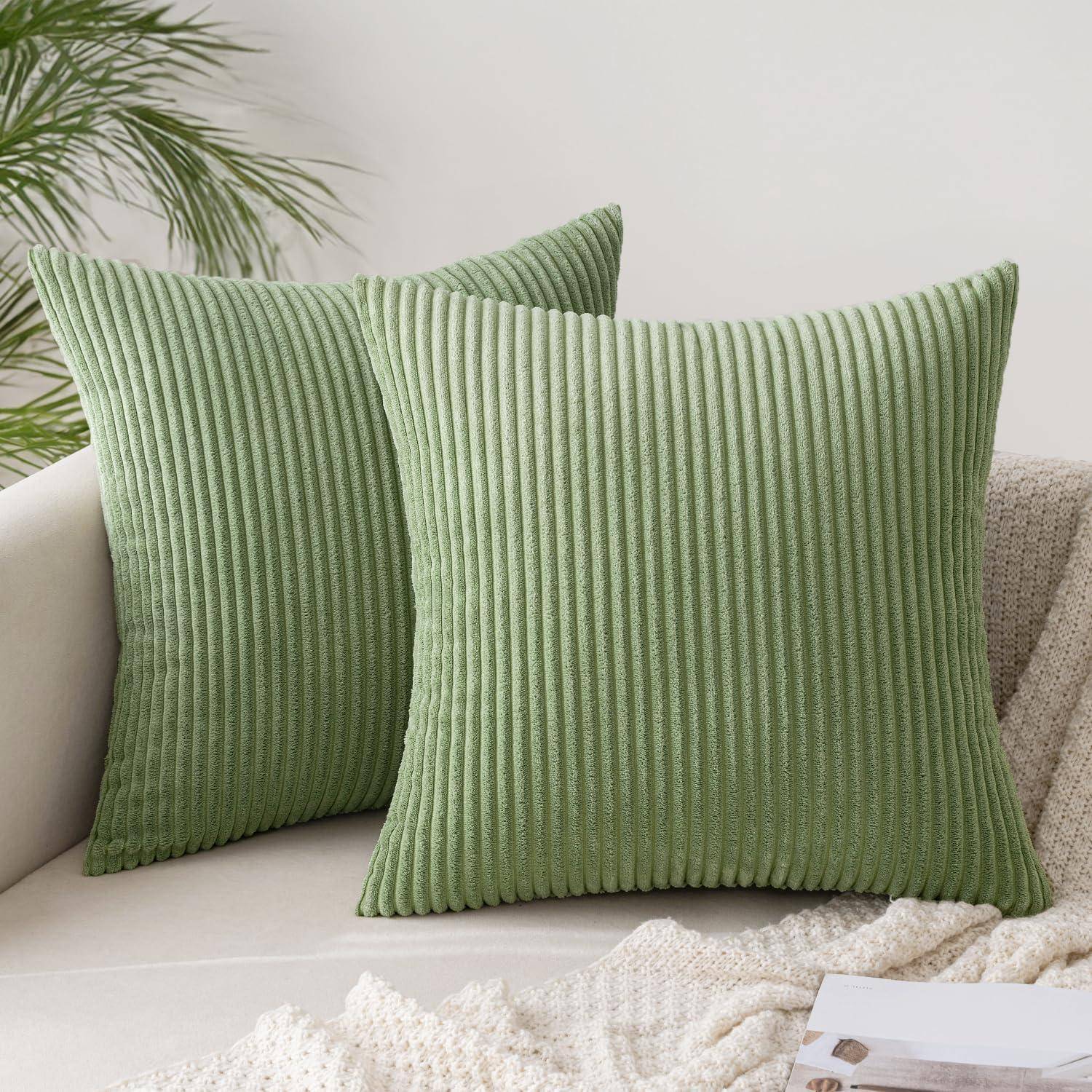 Ein hellgrünes, geripptes Zierkissen in der Ecke eines beigen Sofas, mit einer strukturierten weißen Decke in der Nähe und einer blattreichen Pflanze im Hintergrund.