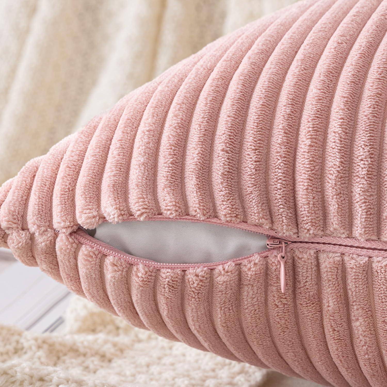 Eine Nahaufnahme eines weichen, rosa Cordkissens mit einem sichtbaren, teilweise offenen Reißverschluss, der den Innenkern des Kissens freilegt. Der Stoff weist vertikale Rillen auf.