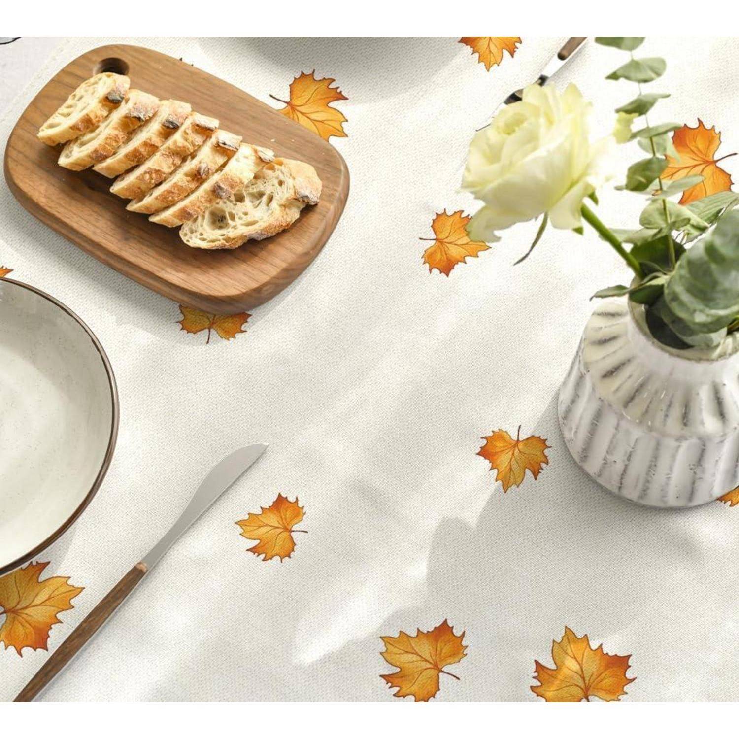 Scheiben Brot auf einem Holzbrett, neben einer weißen Vase mit einer Rose, platziert auf einer Tischdecke mit Herbstblattmustern.