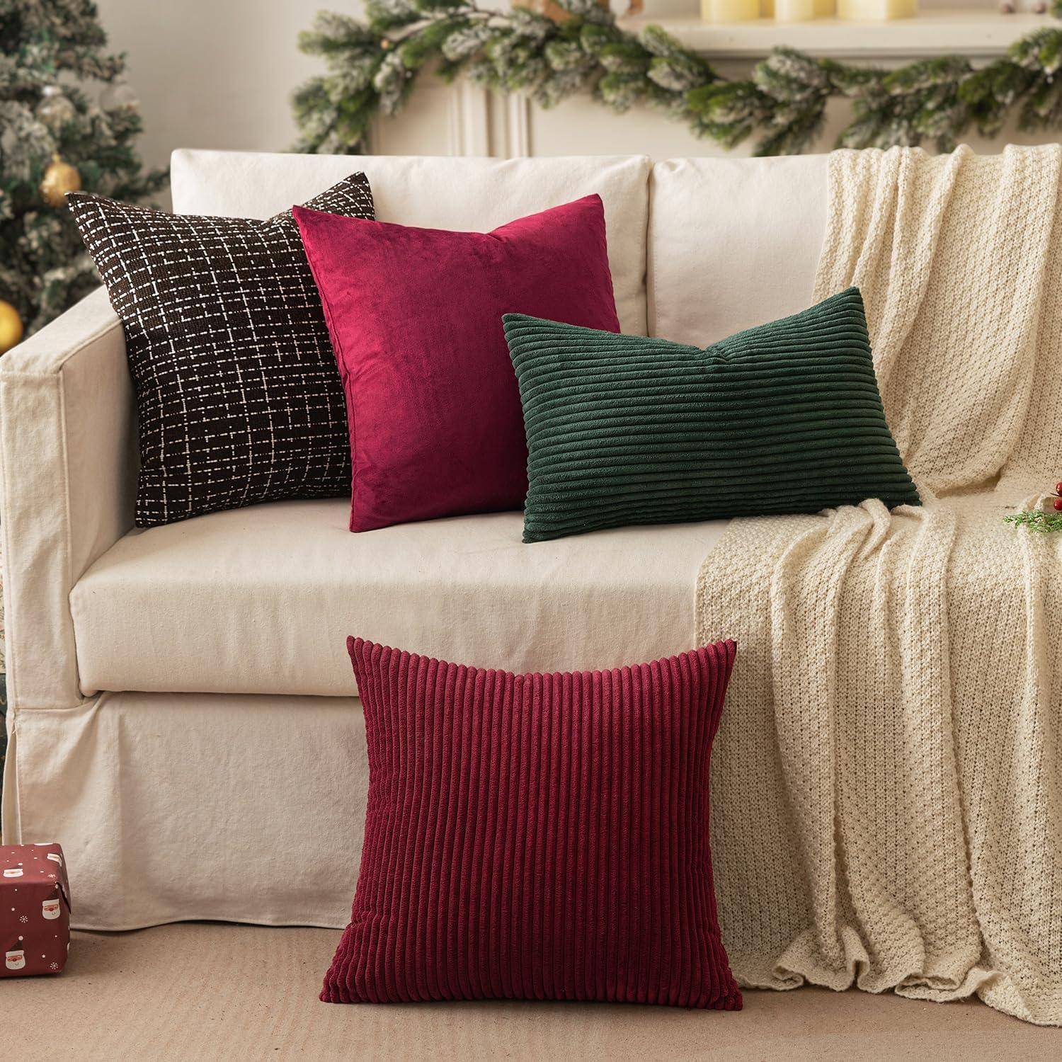 Ein beiger Sofa mit roten, grünen und schwarzen Kissen steht in einem gemütlichen Raum mit Weihnachtsdekoration und einem warmen braunen Boden.