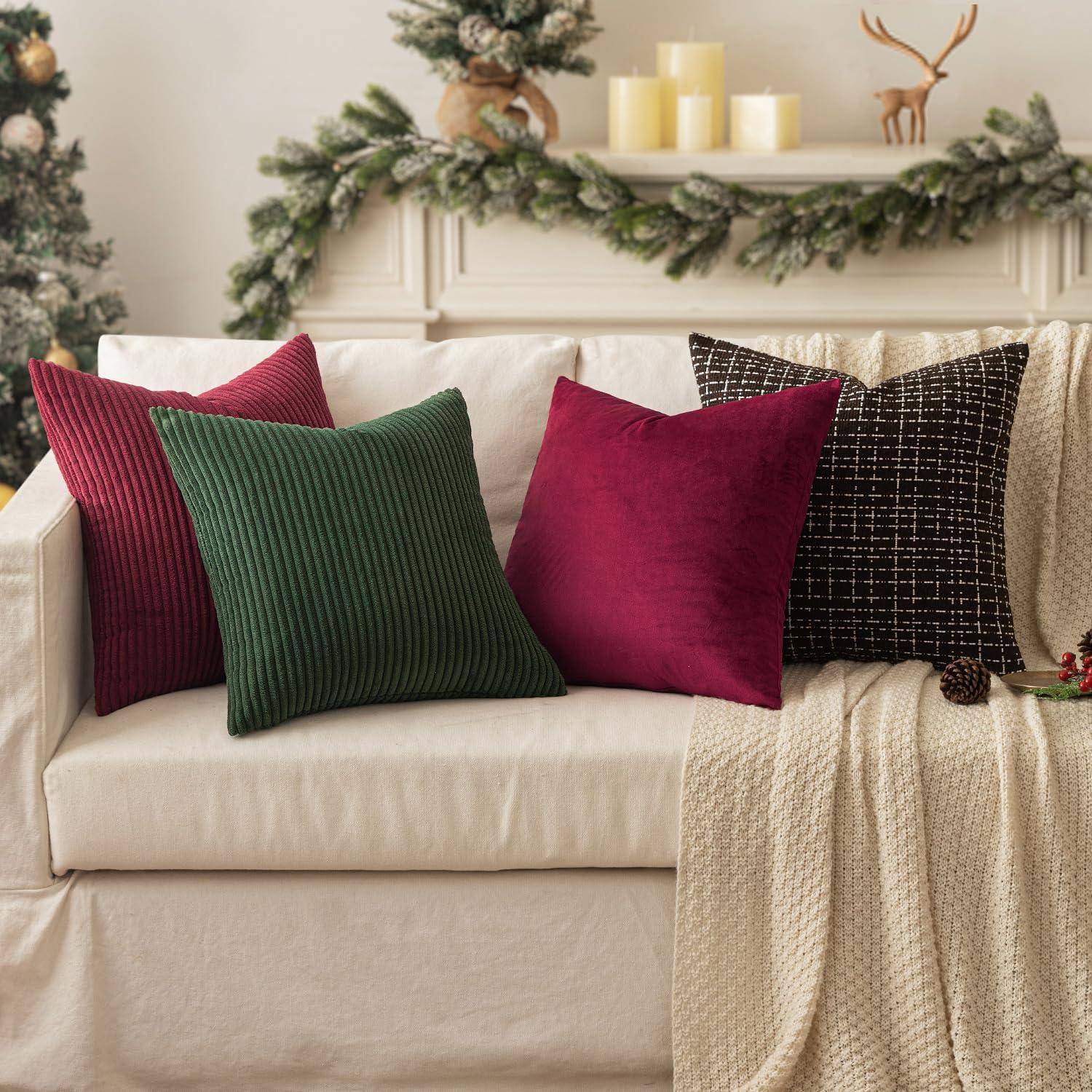 Ein gemütlicher Wohnbereich mit einem weißen Sofa, geschmückt mit roten, grünen und schwarzen Kissen. Girlanden, Kerzen und Christbaumschmuck dekorieren den Hintergrund.