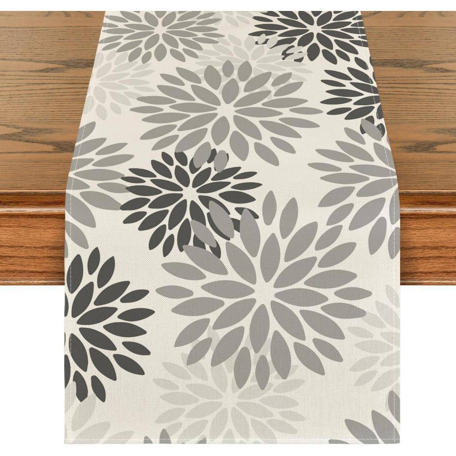 Ein Holztisch mit einem dekorativen Läufer, der ein Muster aus grauen Blumendesigns aufweist.