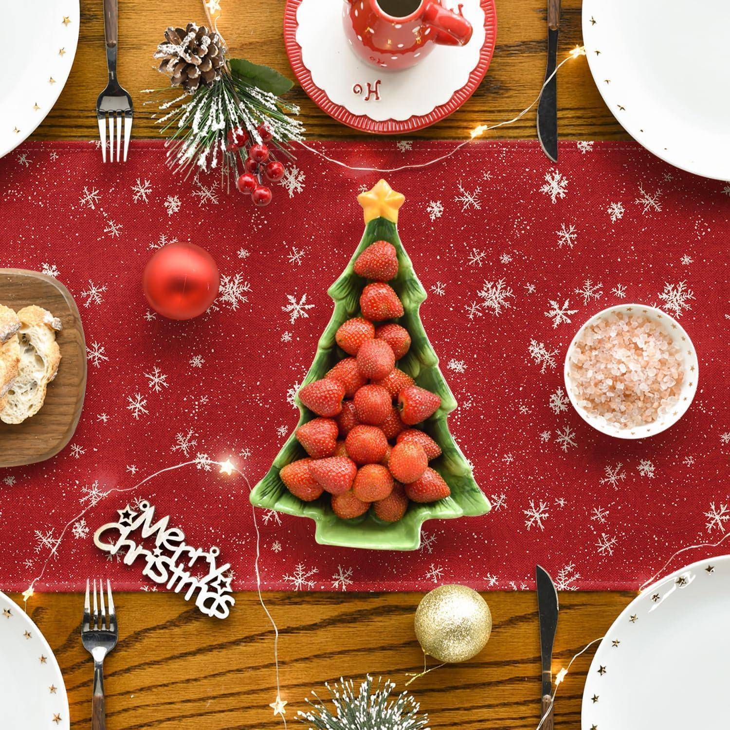 Eine festliche Tischdekoration mit einem roten Läufer, einem weihnachtsbaumförmigen Teller gefüllt mit Erdbeeren und festlichen Dekorationen.