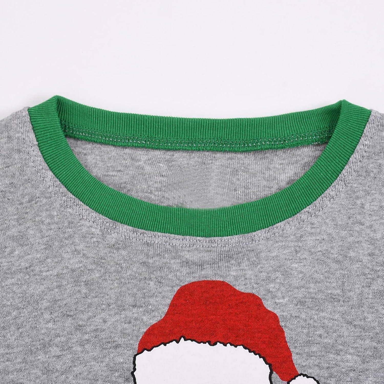 Ein graues T-Shirt mit einem grünen Kragen, das vorne ein Design mit einer roten Weihnachtsmannmütze mit weißem Rand trägt.