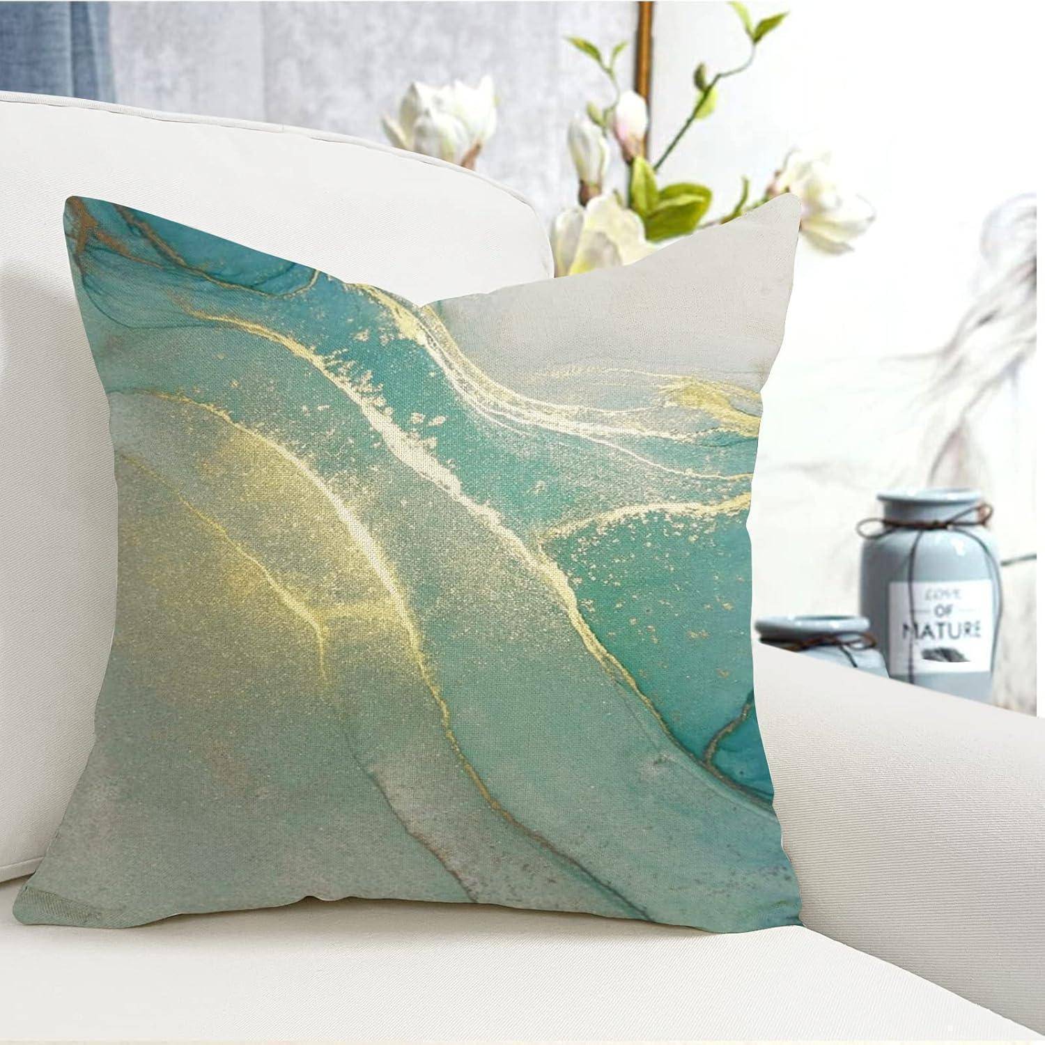 Ein dekorativer Kissenbezug mit einem abstrakten Design, der geschwungene Schattierungen von Blau, Grau und Weiß zeigt, liegt auf einem Bett. Im Hintergrund sind Blumen zu sehen.