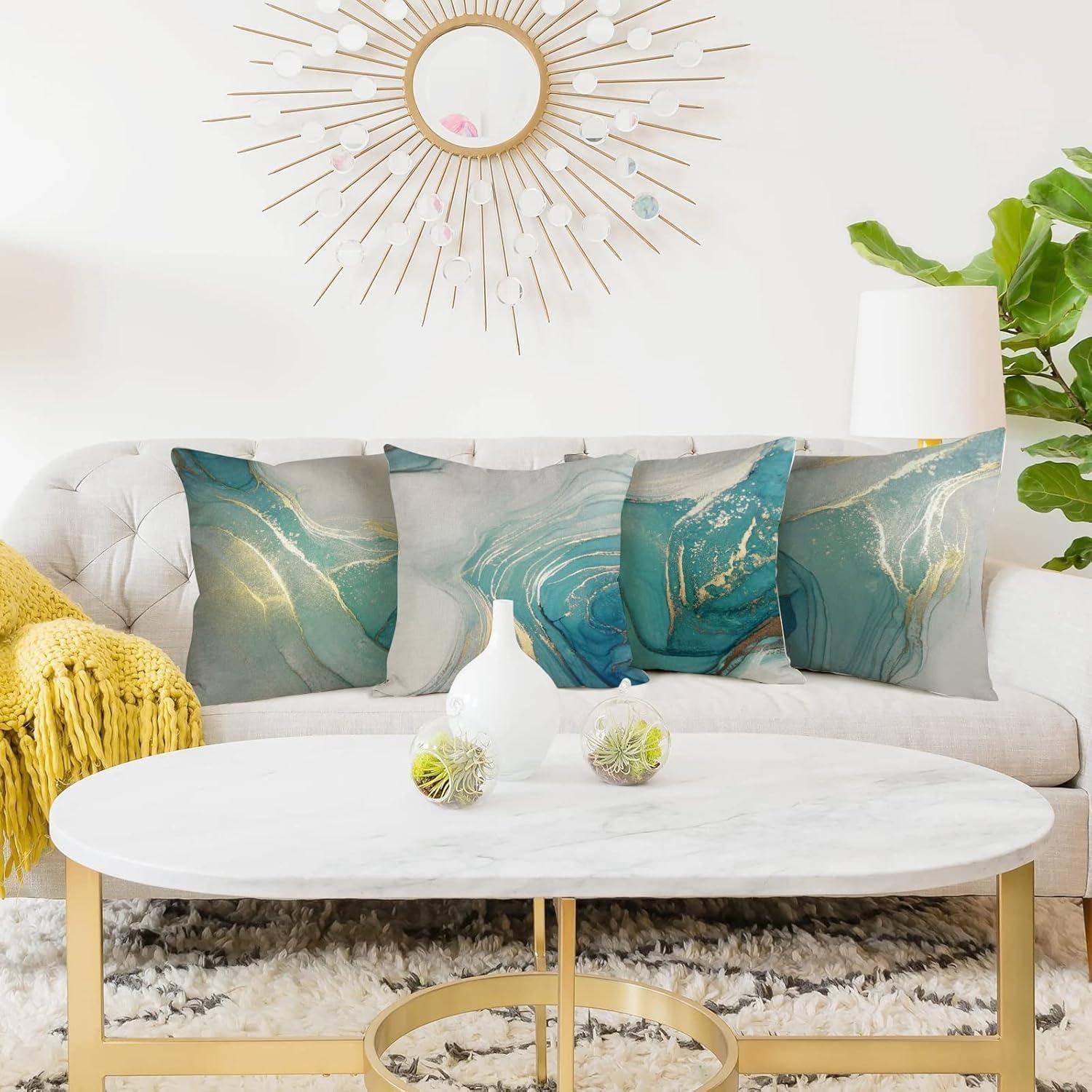 Ein modernes Wohnzimmer präsentiert ein weißes Sofa mit türkis- und grauen gemusterten Zierkissen, einen Marmor-Couchtisch und einen Sonnenspiegel an der Wand.