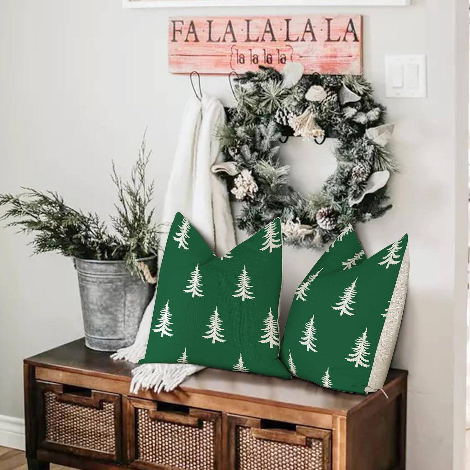 Ein gemütlicher, weihnachtlich gestalteter Eingangsbereich zeigt einen Kranz mit Tannenzapfen, zwei grüne Kissen mit Baummustern auf einer Bank und ein Schild mit der Aufschrift ‚Fa La La La La'.