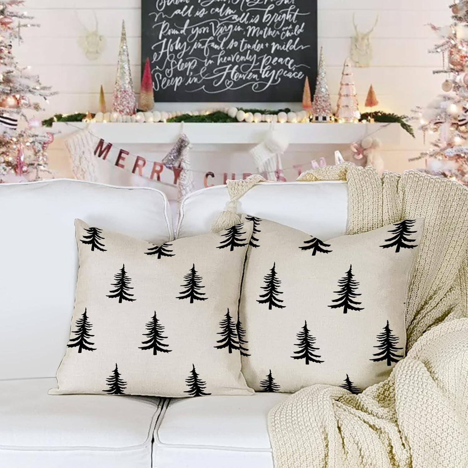 Ein gemütliches Wohnzimmer mit einem weißen Sofa, baumgemusterten Kissen und einer Kuscheldecke. Im Hintergrund ein festlich geschmückter Kaminsims mit einem 'Frohe Weihnachten'-Schild.