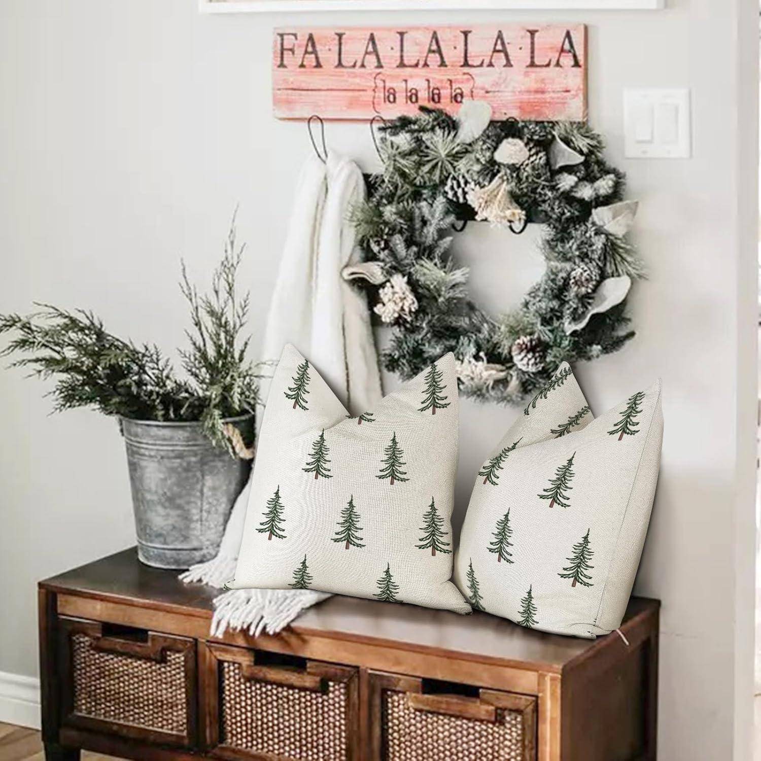 Eine weihnachtlich gestaltete Dekoration mit einem Kranz, einem roten Schild mit der Aufschrift ‚Fa La La La La', zwei Kissen mit Tannengrünmuster und einer kleinen Tanne in einem Eimer.