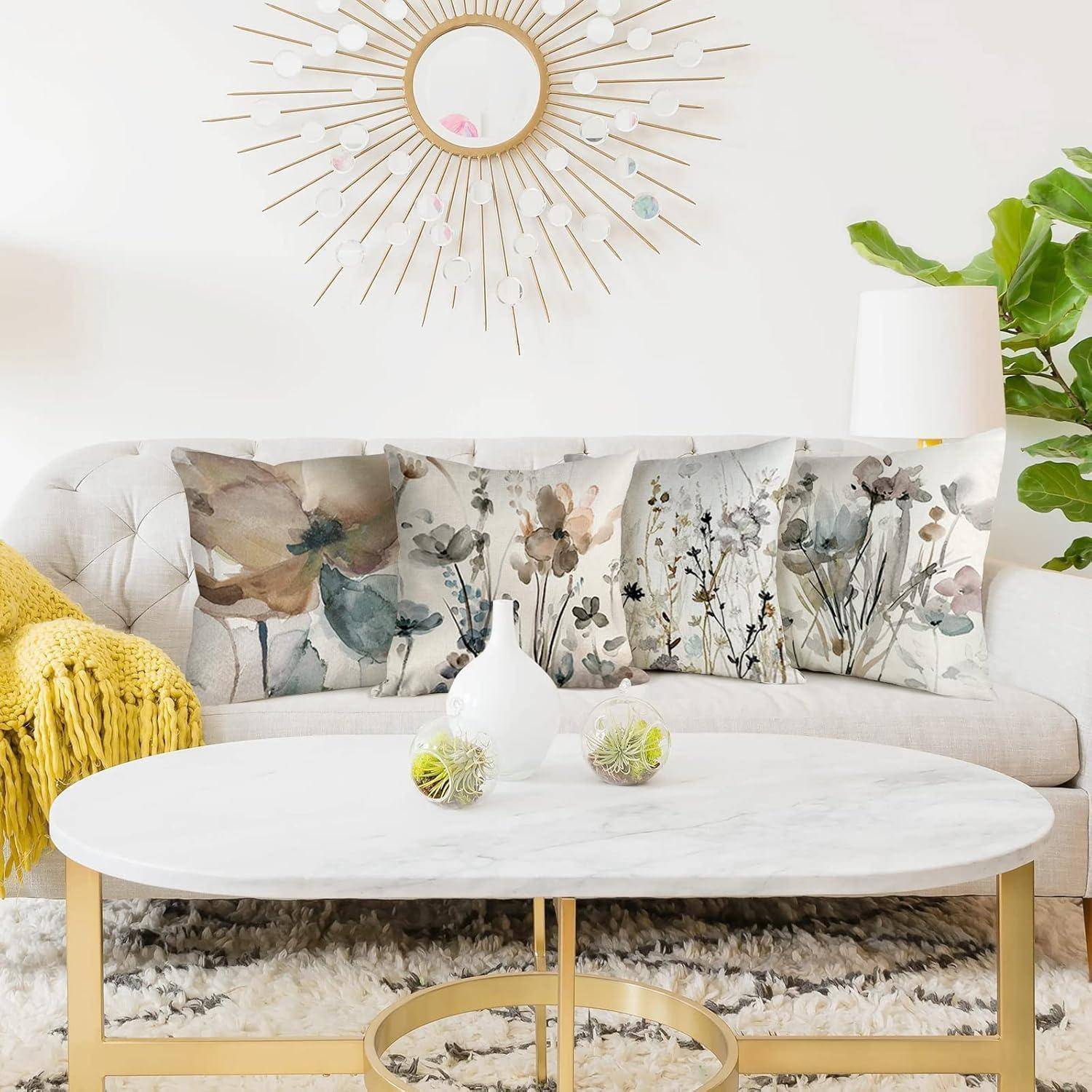 Ein Wohnzimmer mit einem weißen Sofa, geschmückt mit naturthematischen Kissen, einem Marmor-Couchtisch, einer gelben Decke und einem Sonnenspiegel.