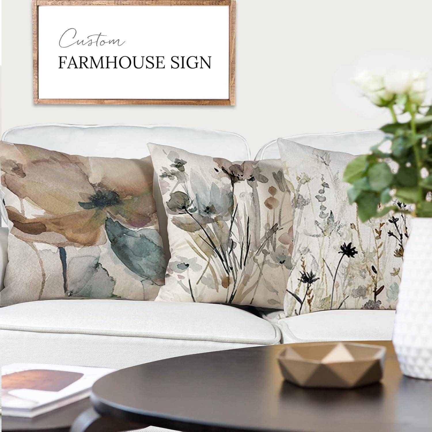 Ein gemütliches Wohnzimmer mit einem weißen Sofa, Blumenkissen und einem Holzcouchtisch. Ein gerahmtes Schild an der Wand trägt die Aufschrift ‚Custom Farmhouse Sign'.