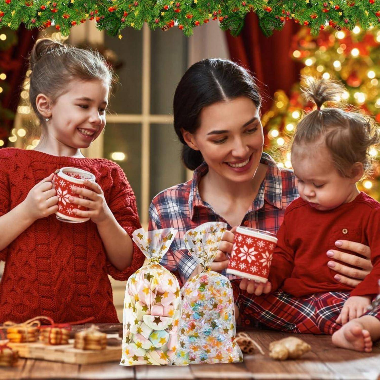 Eine Frau und zwei Kinder in festlicher Kleidung genießen heiße Getränke, umgeben von Weihnachtsdekoration und Geschenktüten auf einem Tisch.