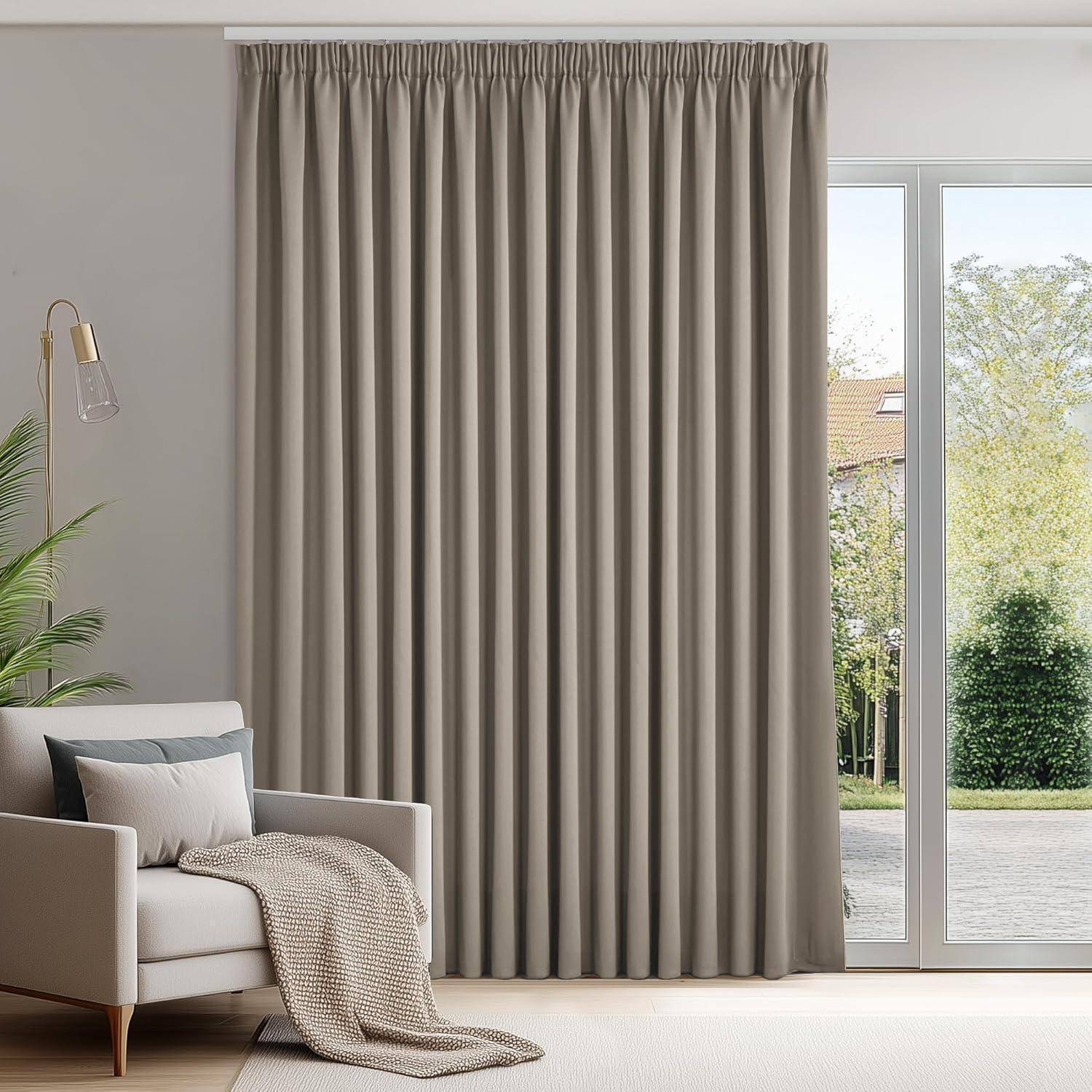 Ein Wohnzimmer mit einem hellgrauen Sofa und einer hohen Stehlampe links. Große Fenster rechts sind mit bodenlangen beigen Vorhängen verhängt.