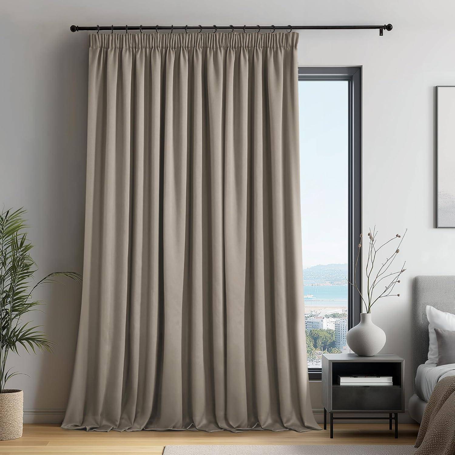 Ein beiger Vorhang verdeckt ein hohes Fenster neben einem grauen Sofa mit Kissen und einem Beistelltisch, auf dem eine weiße Vase mit Zweigen steht.