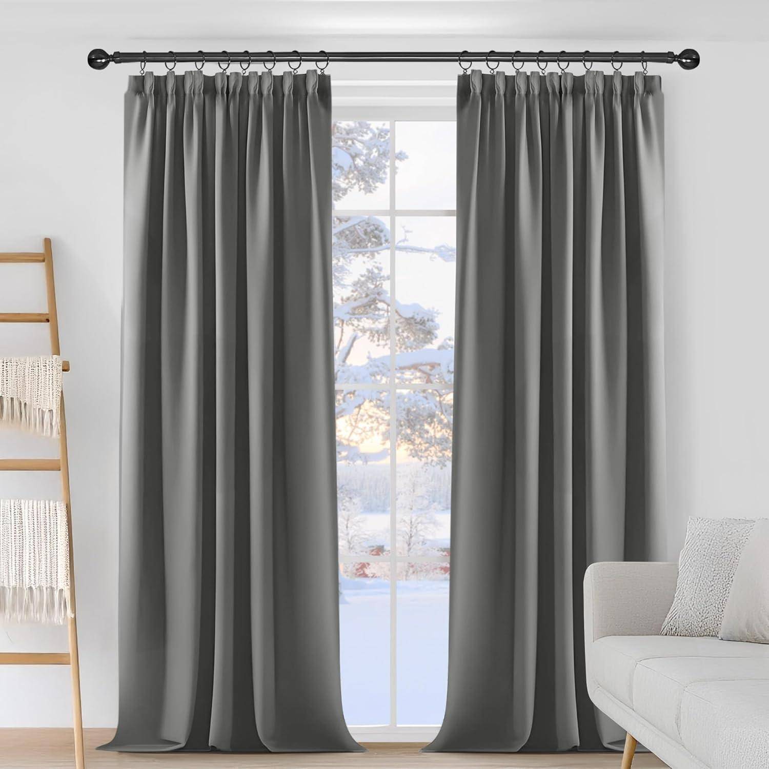 Raum mit grauen Vorhängen und einem Fenster, das eine verschneite Landschaft von draußen zeigt; ein weißer Sessel und ein Holzleiterregal im Vordergrund.