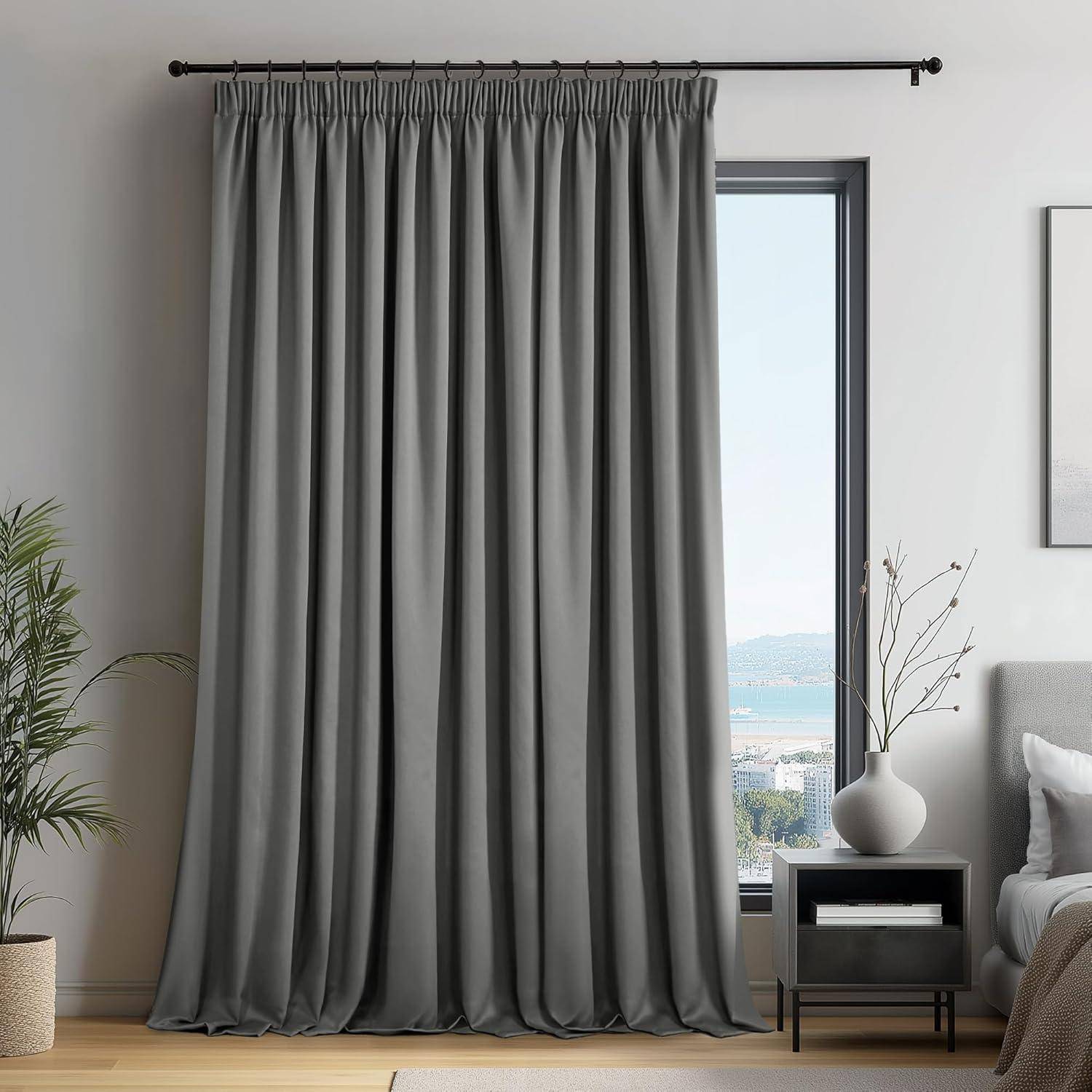 Ein modernes Wohnzimmer mit geschlossenen grauen Vorhängen an einem großen Fenster. Ein kleiner Beistelltisch trägt eine dekorative weiße Vase mit minimalistischen Zweigen.