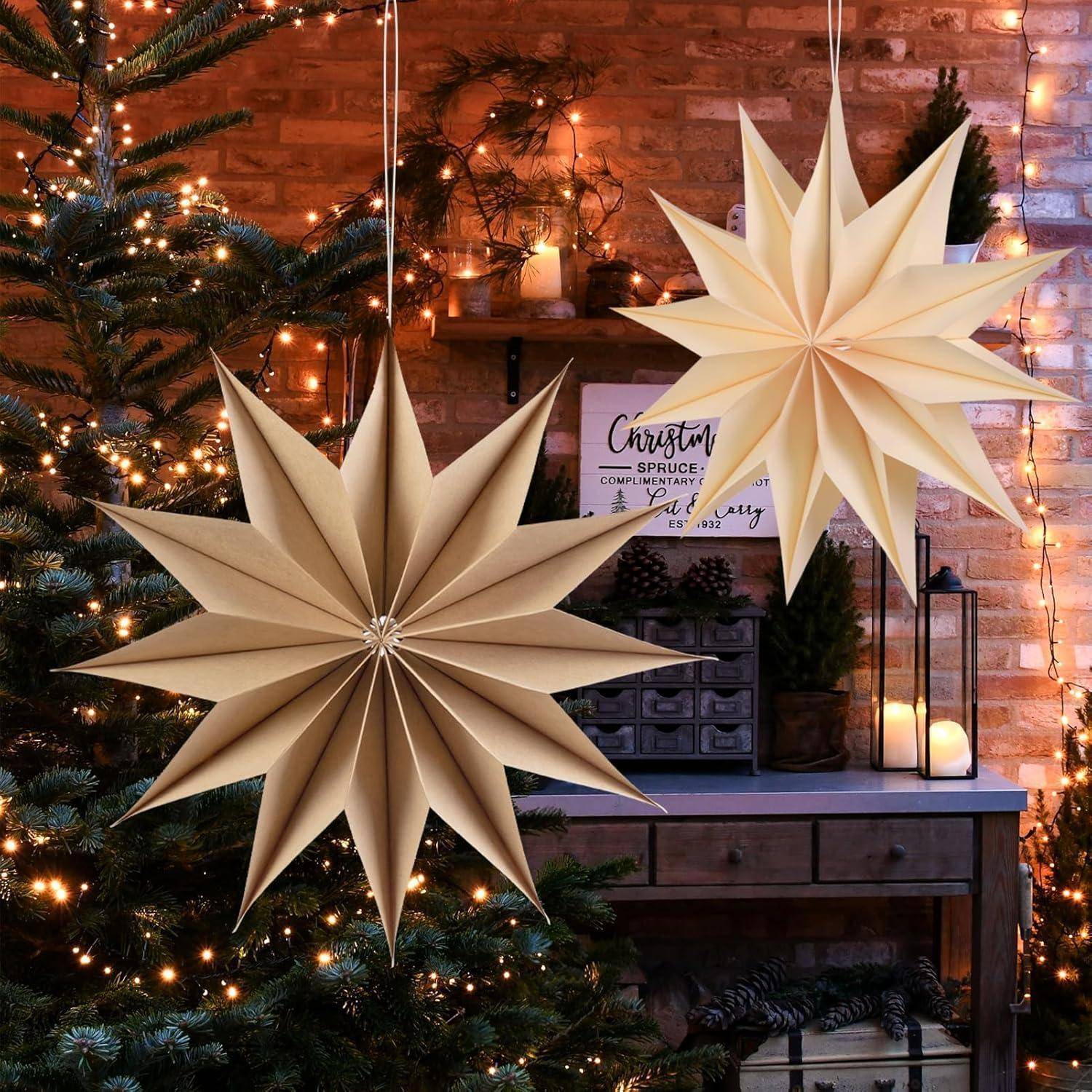 Papiersterne hängen vor einem geschmückten Weihnachtsbaum mit Lichtern, Kerzen und einem Schild, auf dem 