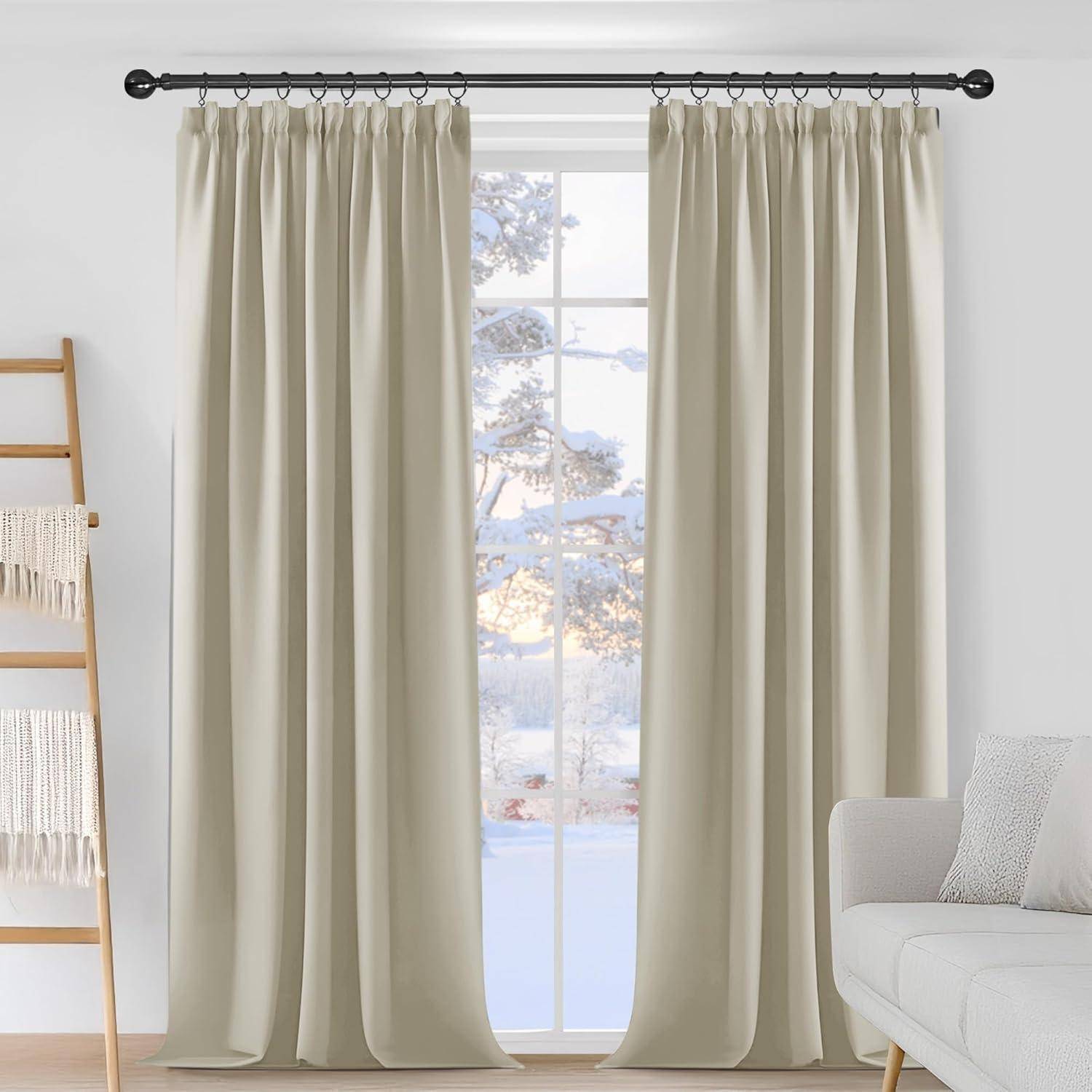 Ein Wohnzimmer mit bodenlangen beigen Vorhängen, die ein Fenster mit einer verschneiten Landschaftsansicht umrahmen. Ein weißes Sofa ist teilweise rechts zu sehen.
