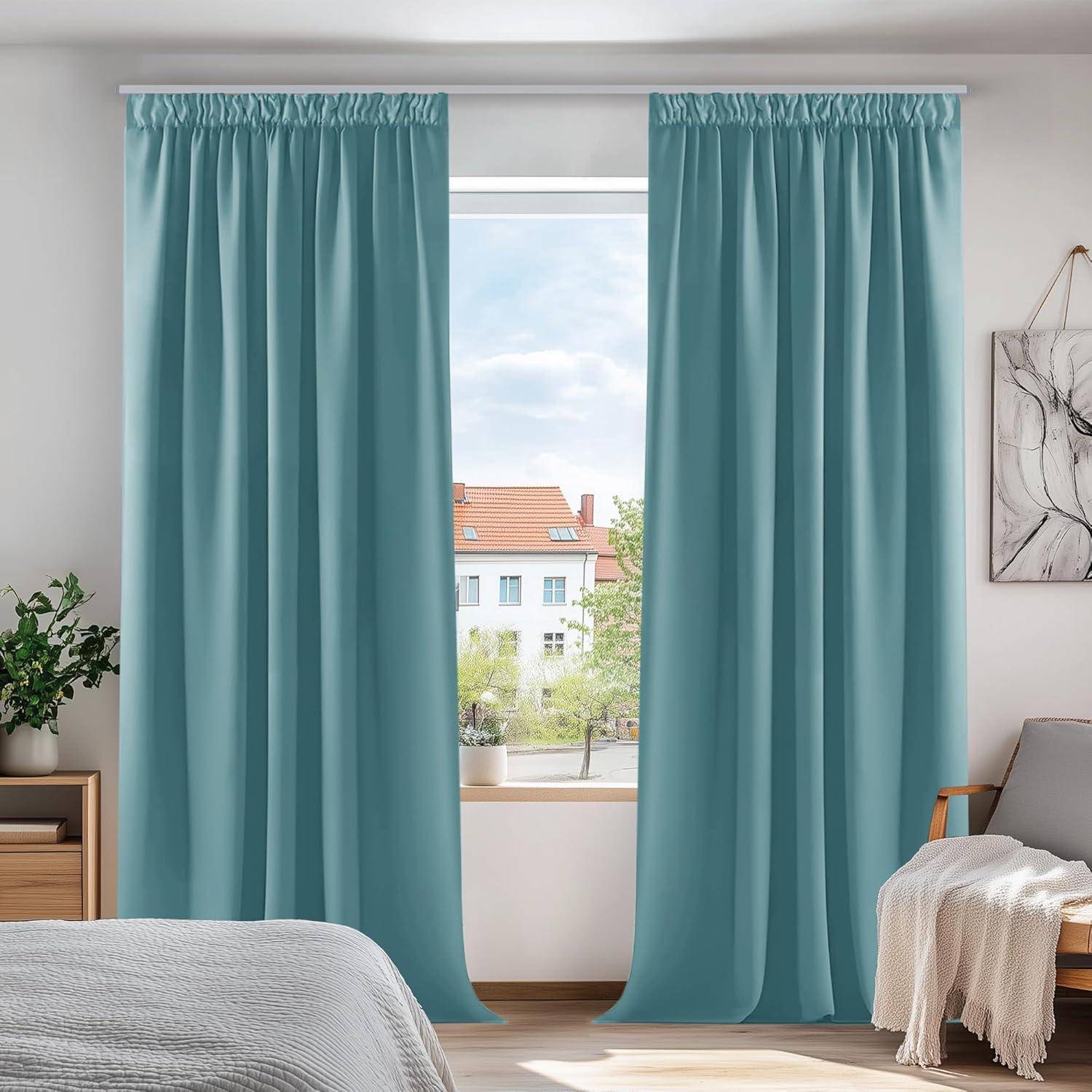 Ein Schlafzimmer mit hellblauen Vorhängen, die ein Fenster mit Blick auf eine Straße umrahmen. Ein Bett mit weißer Bettwäsche befindet sich im Vordergrund, und an der Wand hängt ein Gemälde.