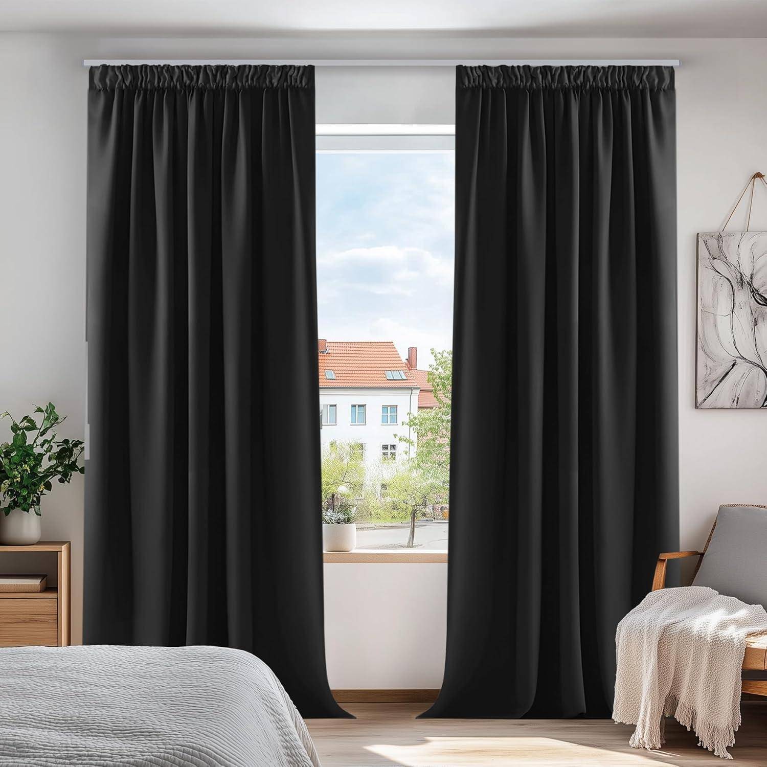 Ein Raum mit einem ordentlich gemachten Bett, schwarzen Vorhängen, die ein Fenster umrahmen und einen Blick auf Gebäude freigeben, und sanft eindringendem Licht.