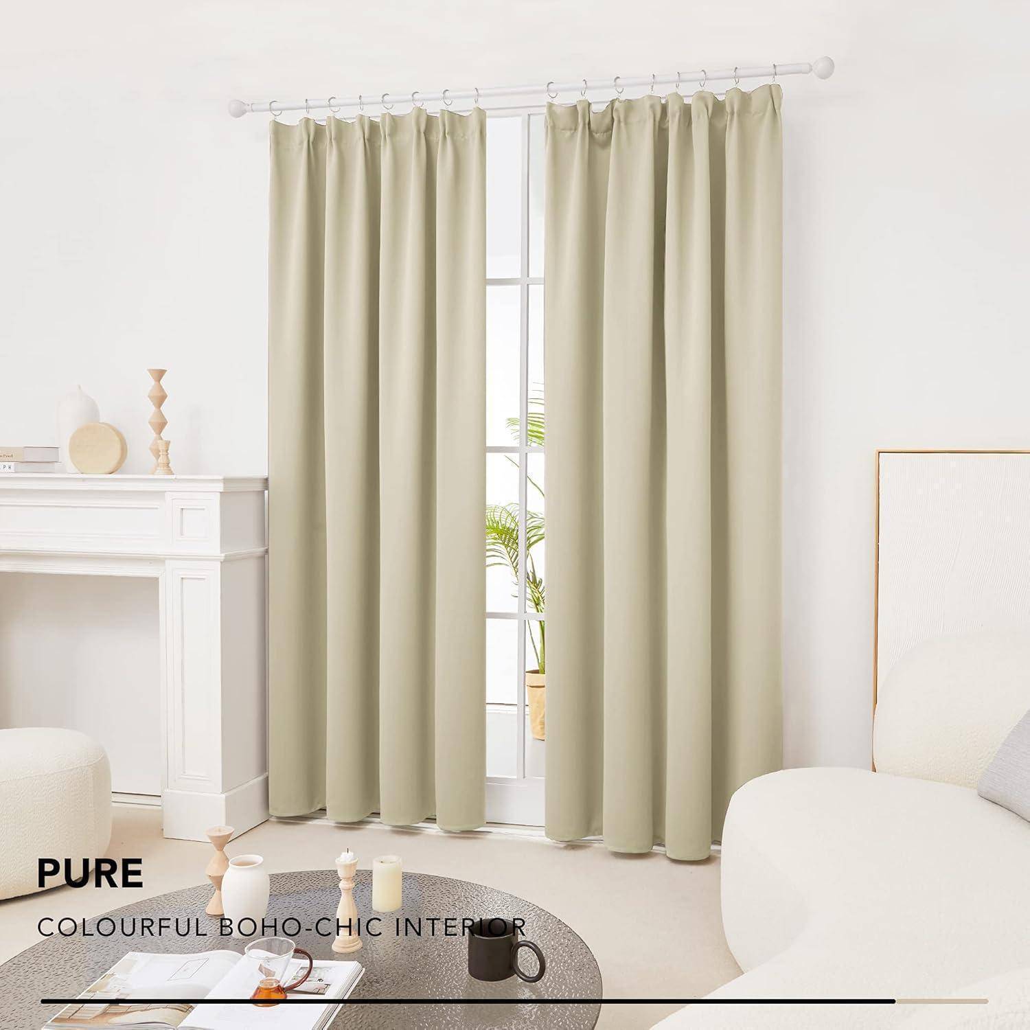 Beige-Vorhänge hängen in einem hellen, minimalistischen Wohnzimmer mit weißen Möbeln und heller Dekoration und schaffen eine Boho-Chic-Atmosphäre.