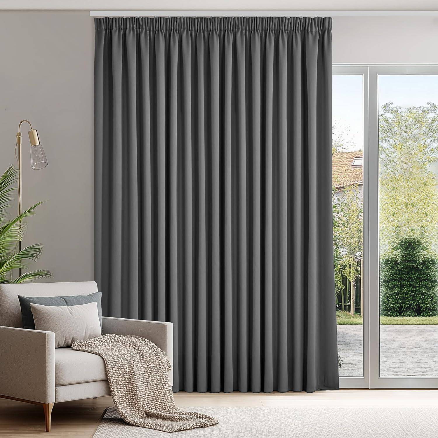 Ein Wohnzimmer mit einem beigen Sofa und grauen Vorhängen. Eine Lampe steht neben dem Sofa, und große Fenster geben den Blick auf Bäume draußen frei.