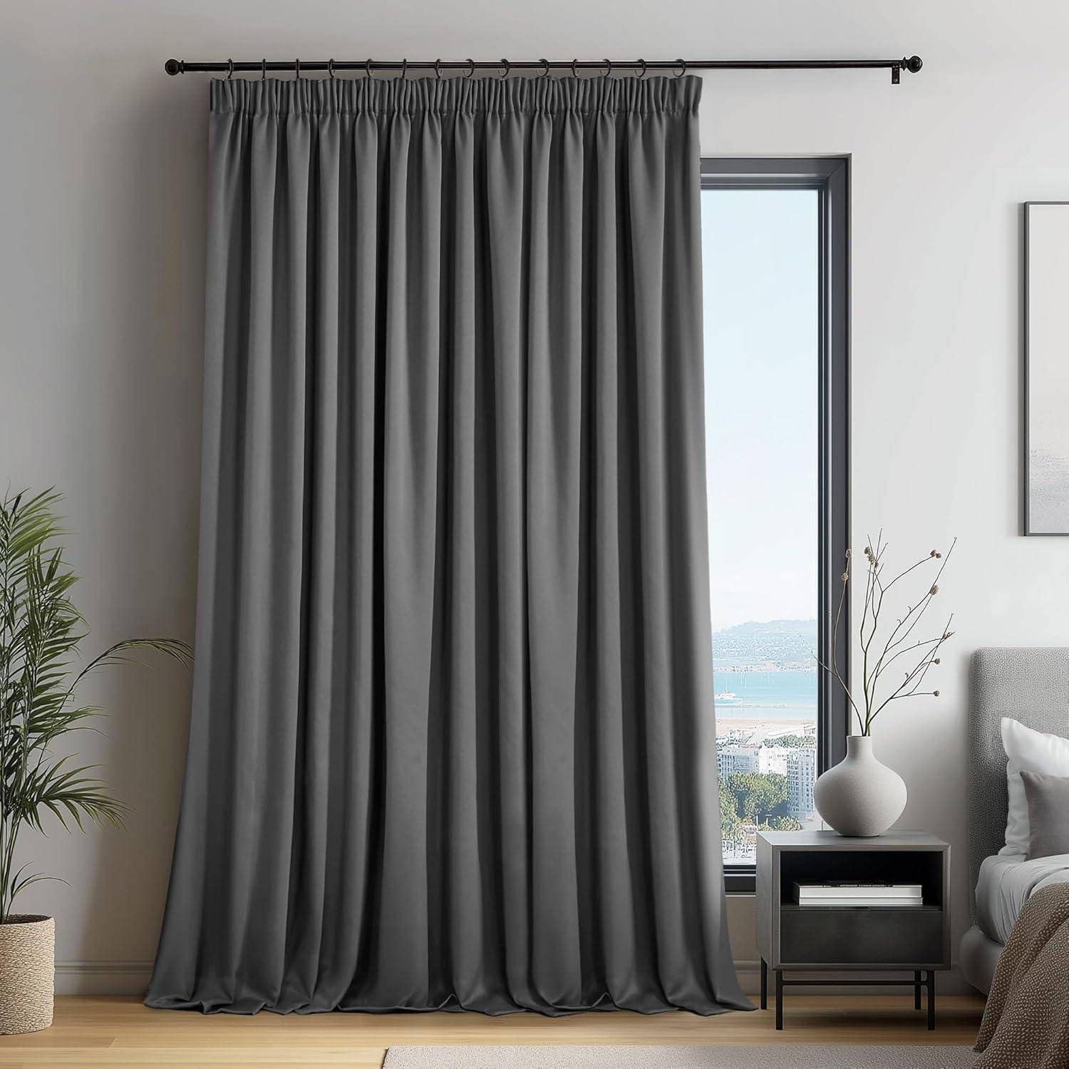 Ein moderner Wohnraum zeigt einen dunkelgrauen Vorhang, der teilweise vor einem Fenster zugezogen ist, mit einem Blick auf eine Meeresaussicht dahinter. Ein Beistelltisch trägt eine Vase mit Zweigen, und ein Sofa ist zu sehen.