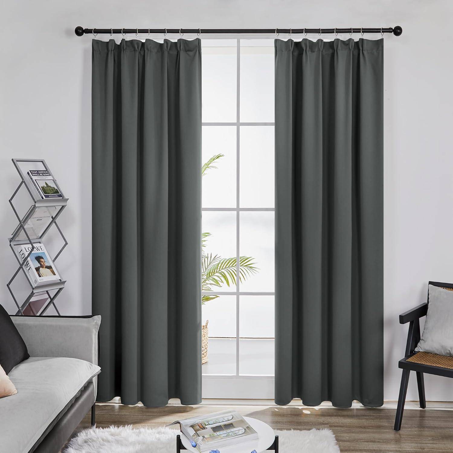Ein Wohnzimmer mit grauen Vorhängen am Fenster, einem Sofa links und einem Stuhl rechts. Ein kleiner Tisch steht vorne mit Zeitschriften.