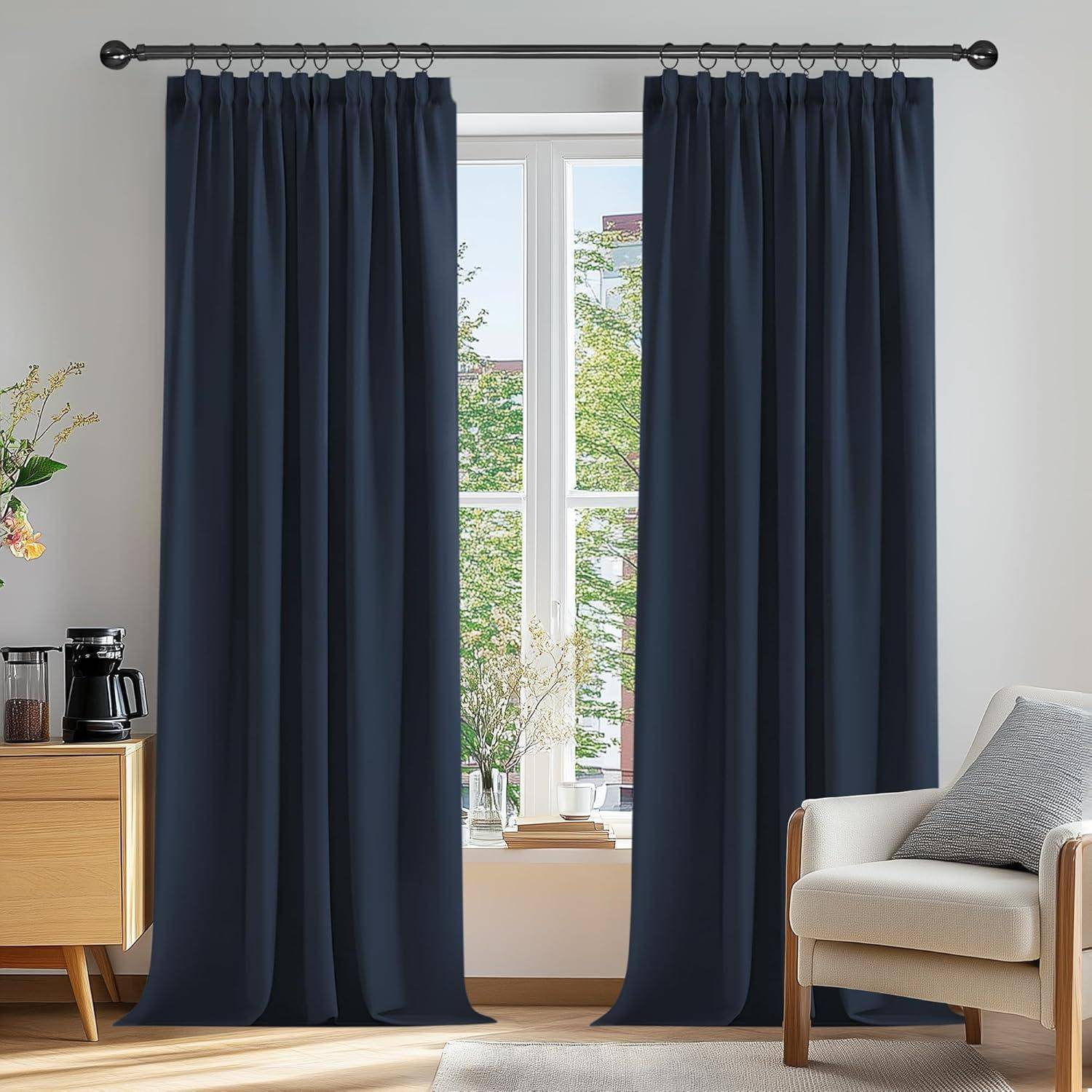 Große marineblau Vorhänge rahmen ein Fenster mit Blick auf grüne Bäume ein. Ein beiger Sessel und ein kleiner Tisch mit einer Kaffeemaschine stehen in der Nähe.
