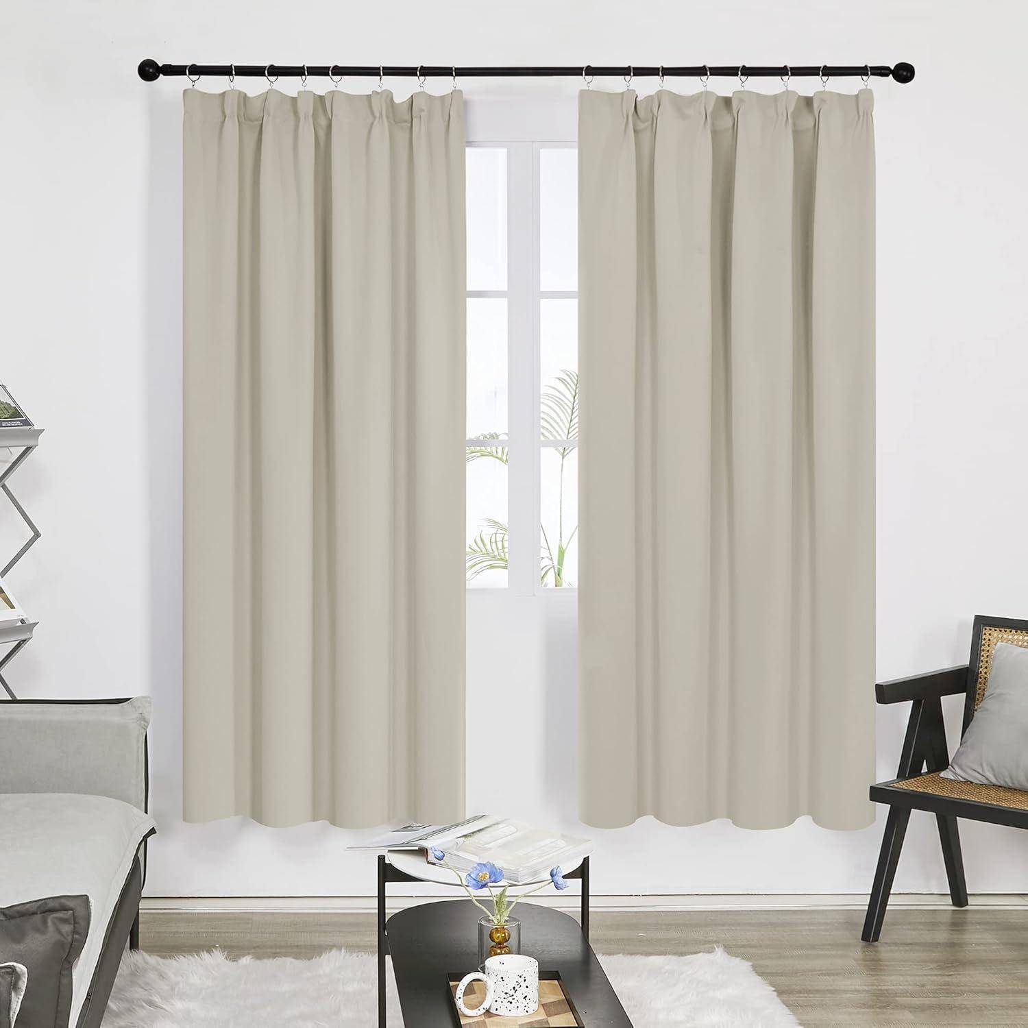 Ein Wohnzimmer mit hellbeigen Vorhängen am Fenster, einem kleinen Couchtisch mit Dekoration, einem grauen Sofa und einem modernen Sessel.
