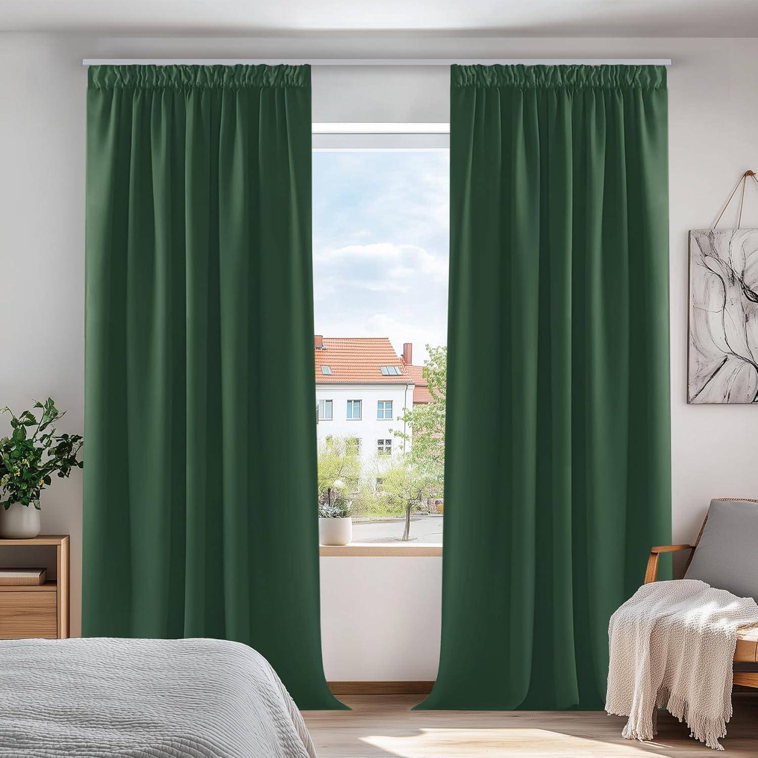 Ein Raum mit grünen Vorhängen, die ein Fenster verhüllen, eine Zimmerpflanze auf dem Nachttisch, ein Bett mit weißer Bettwäsche und Wandkunst auf der rechten Seite.