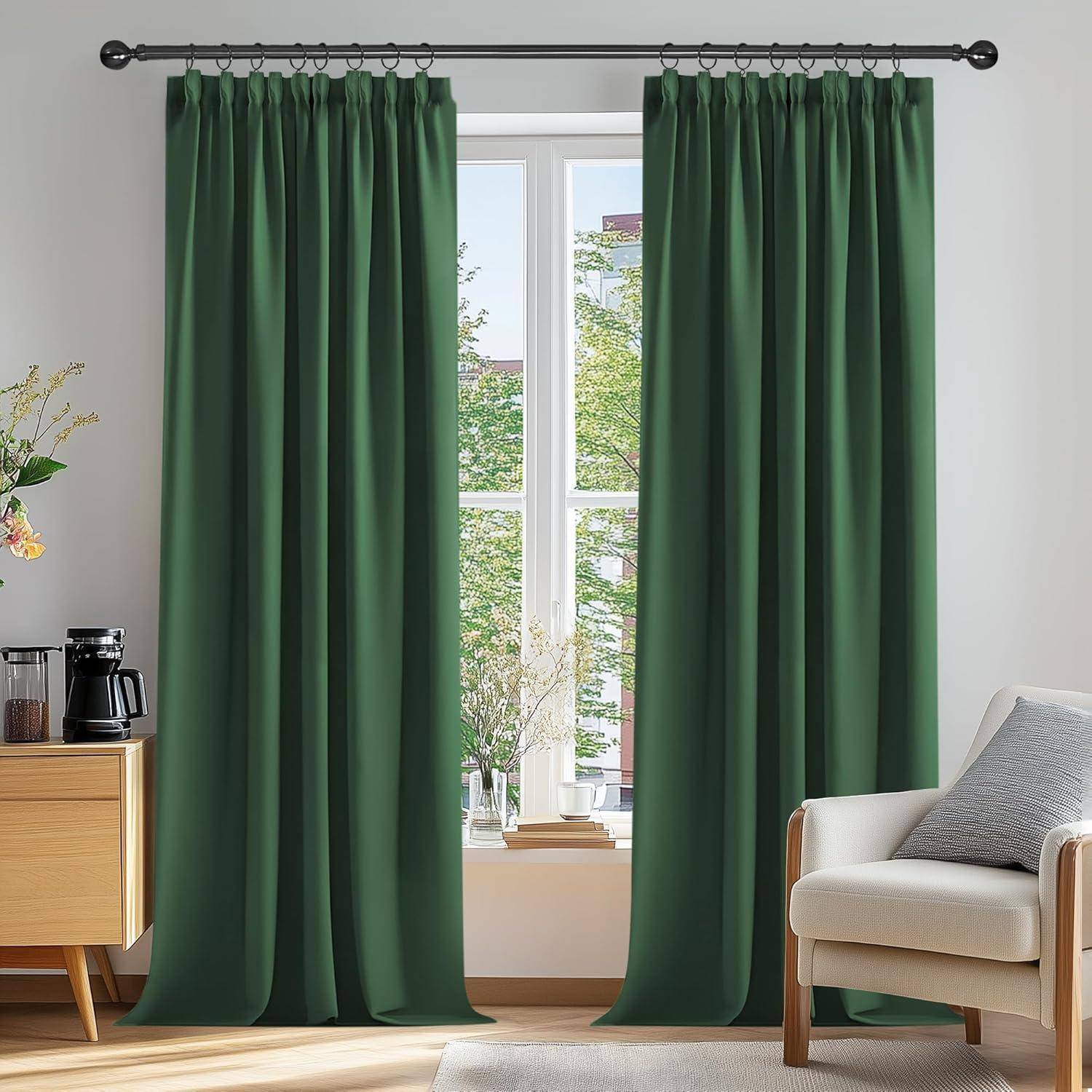 Ein Raum mit großen grünen Vorhängen, die ein Fenster verhüllen, einem weißen Sessel, einem Holzschrank mit einer Kaffeemaschine und einer Pflanze, der eine gemütliche Atmosphäre verleiht.