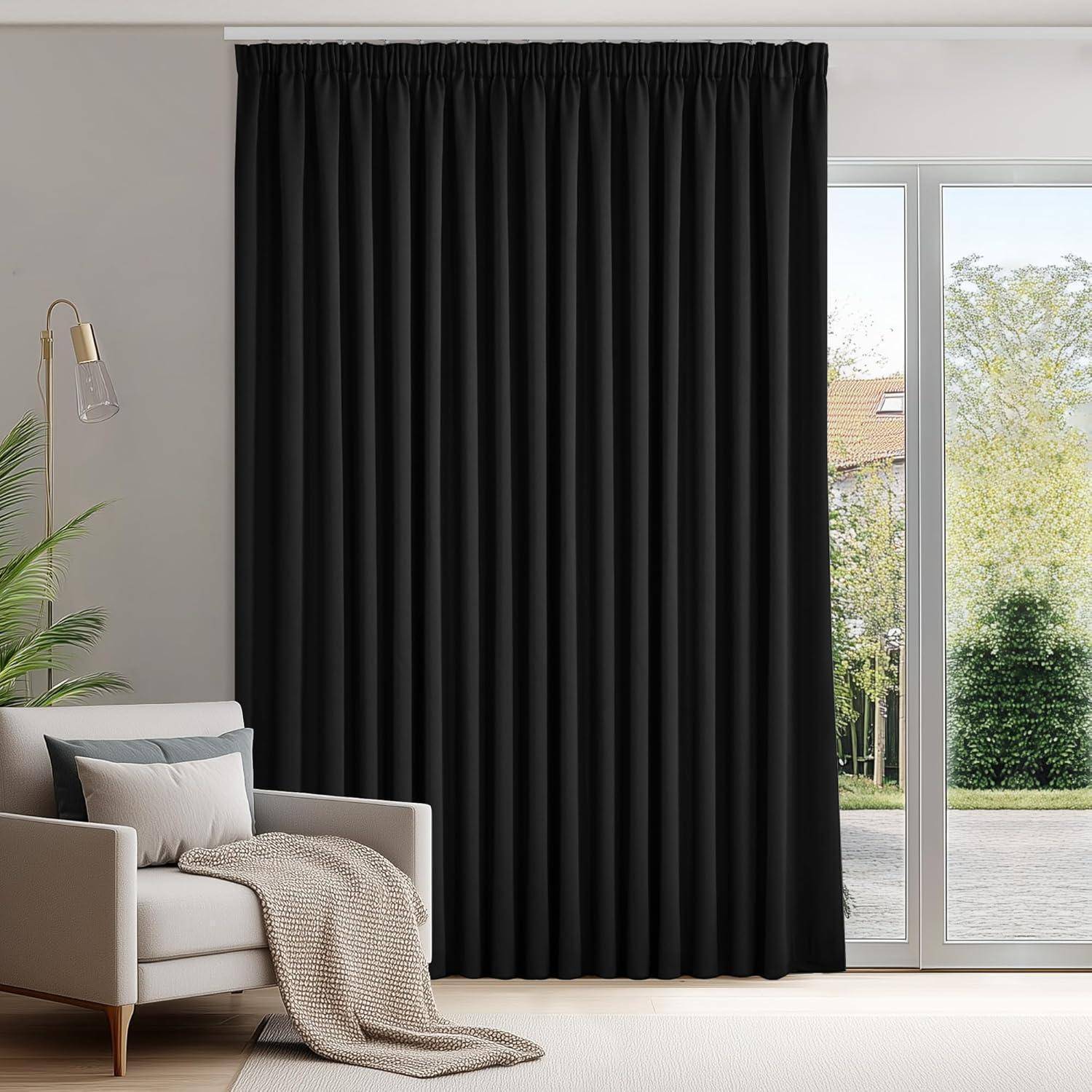 Ein gemütliches Wohnzimmer zeigt ein Sofa mit einem Kissen und einer Decke, eine Stehlampe und schwarze Vorhänge an einem großen Fenster, das einen Gartenblick bietet.