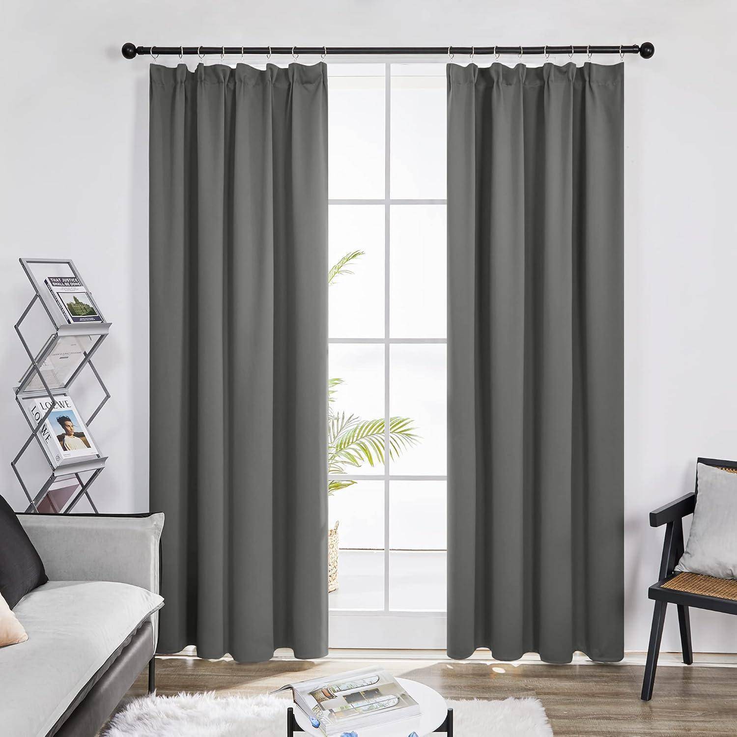 Wohnzimmer mit grauen Vorhängen an einem großen Fenster, einem schwarzen gepolsterten Sessel, einem kleinen Beistelltisch und einem Zeitschriftenständer.
