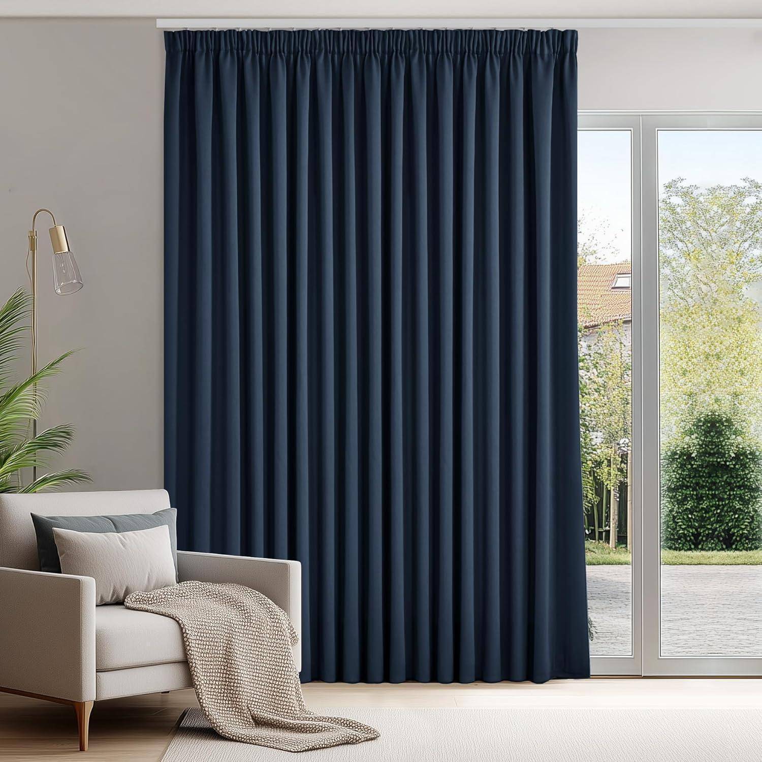 Ein gemütliches Wohnzimmer mit einem beigen Sofa, einer drappierten Decke, einer hohen Stehlampe und einem großen Fenster, das von dunkelblauen Vorhängen verdeckt wird und einen Blick in den Garten freigibt.