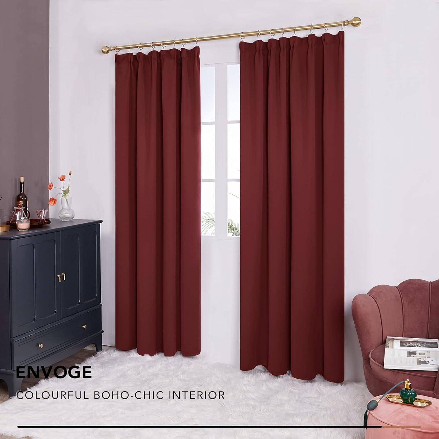 Ein Raum mit roten Vorhängen, einem dunklen Schrank mit Dekorationsstücken, einem rosa Sessel und einem weißen, zottligen Teppich, beschrieben als ‚buntes Boho-Chic-Interieur'.