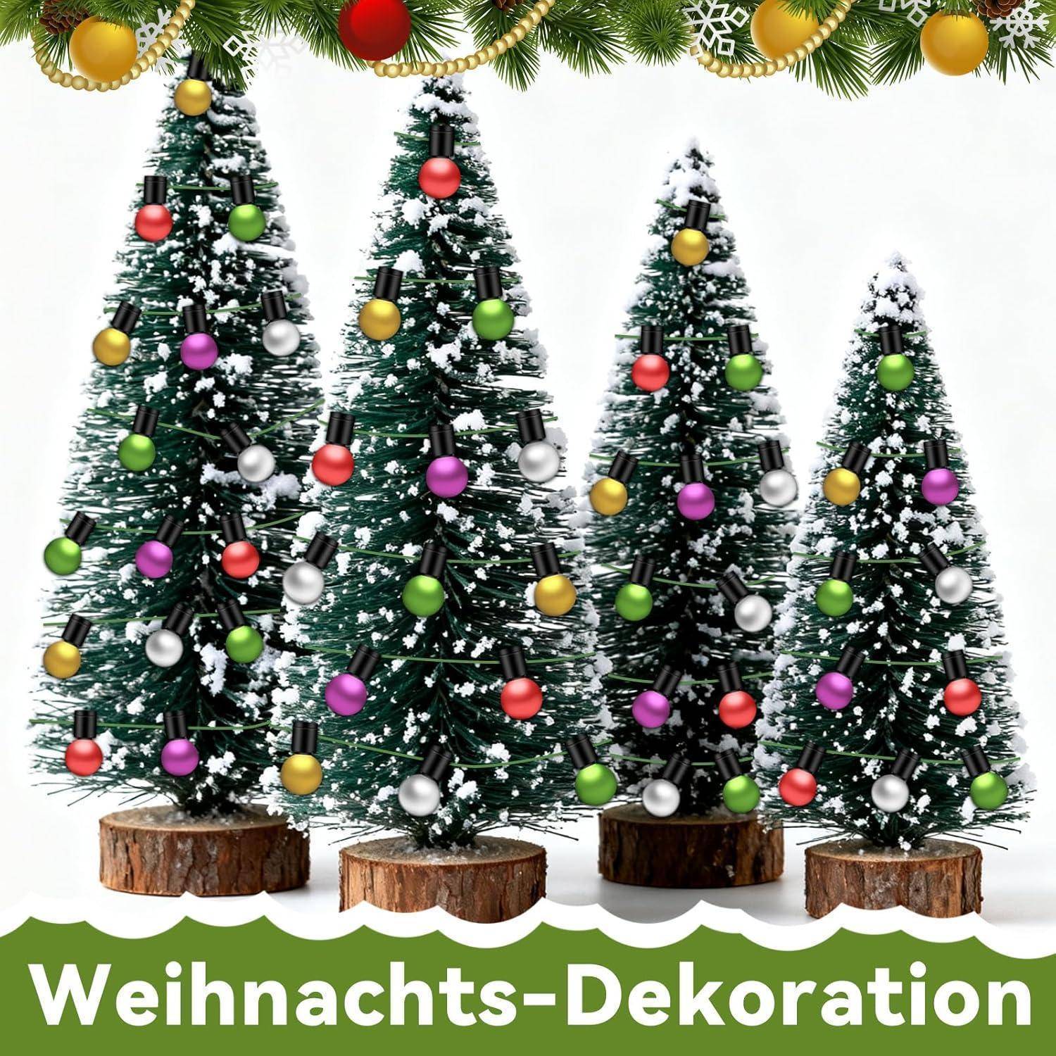 Vier mit Schnee bedeckte Weihnachtsbäume mit bunten Weihnachtskugeln stehen auf Holzständern. Der deutsche Text darunter liest sich 