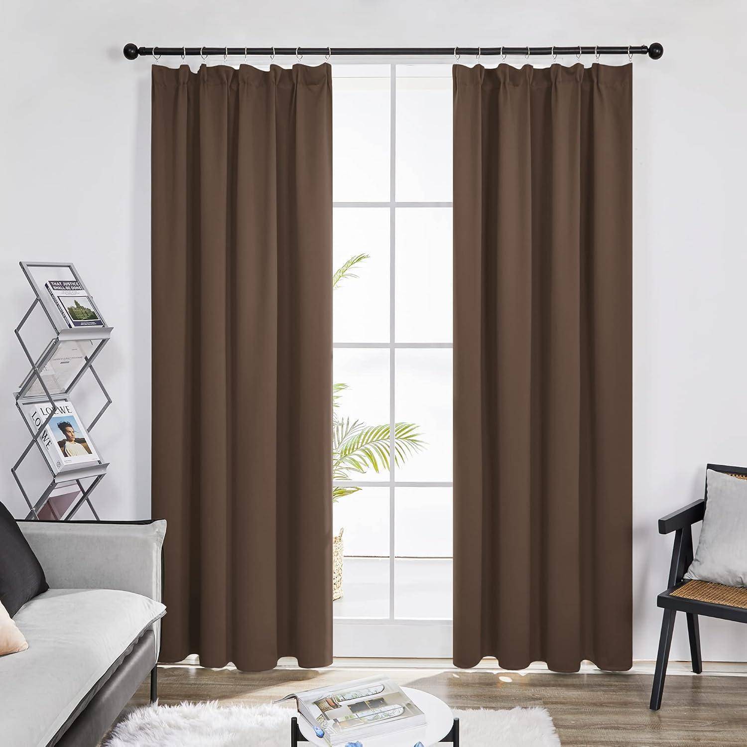Braune Vorhänge hängen an einem Fenster mit Ausblick auf Pflanzen draußen. Der Raum enthält ein Sofa, einen Sessel, einen kleinen Tisch und einen Zeitschriftenständer.